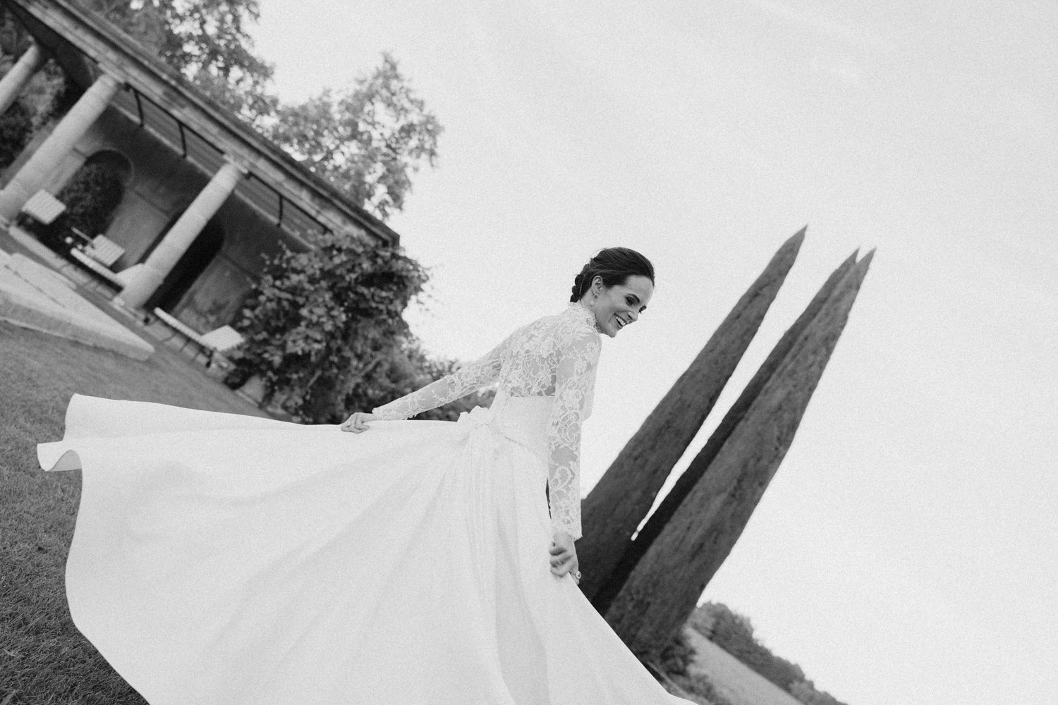 Wedding dress flows elegantly in black and white outdoor portrait.