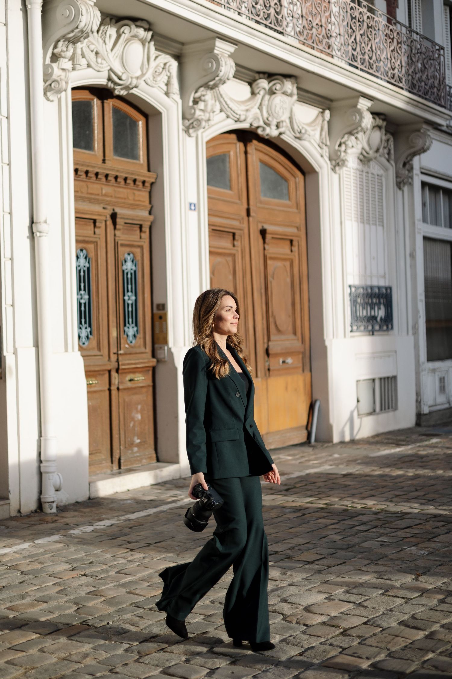 Dynamic fashion poses captured along historic building facade in natural lighting.