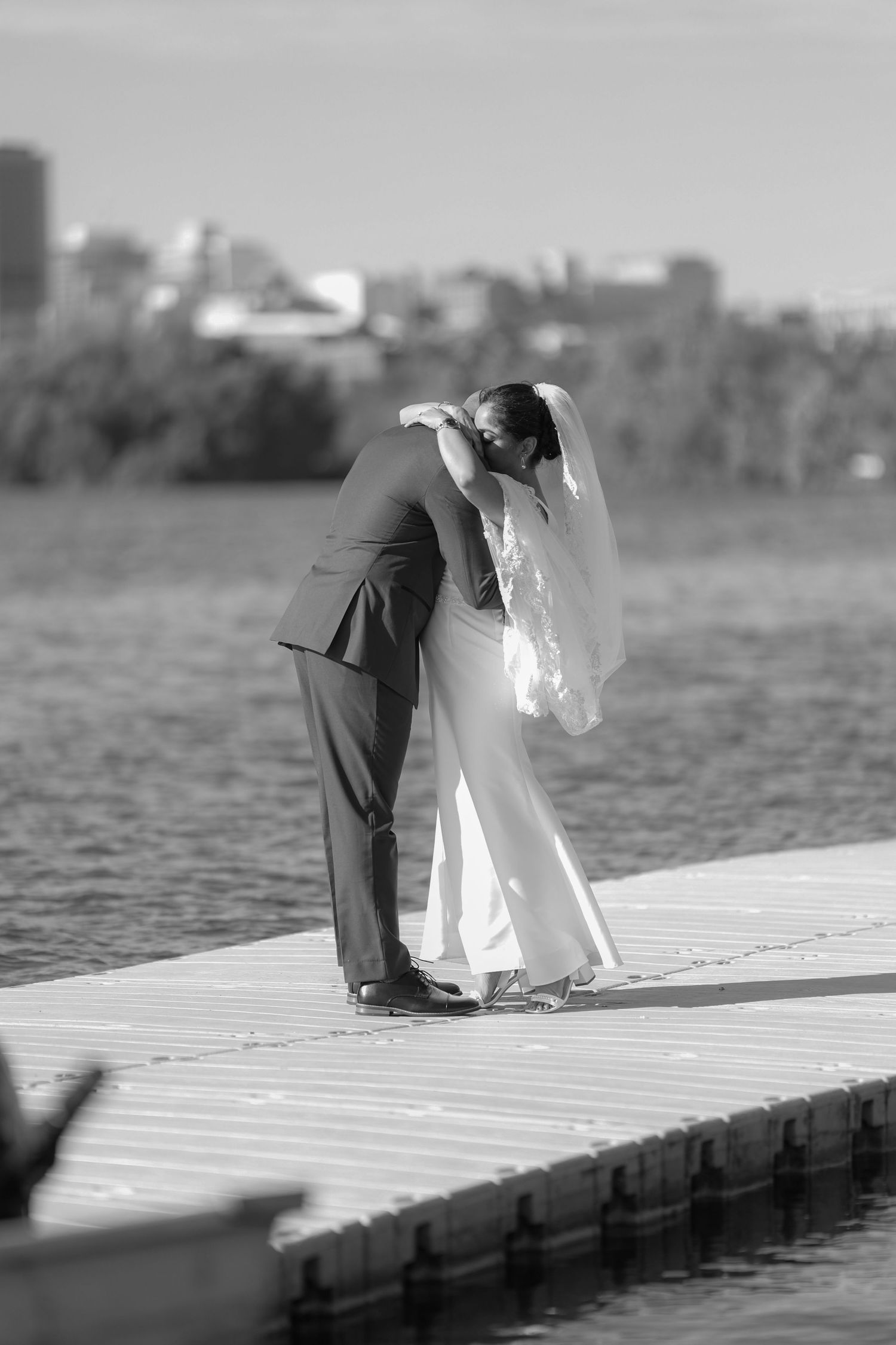 A romantic black and white photograph shows a couple sharing an intimate moment on a wooden dock by the water.