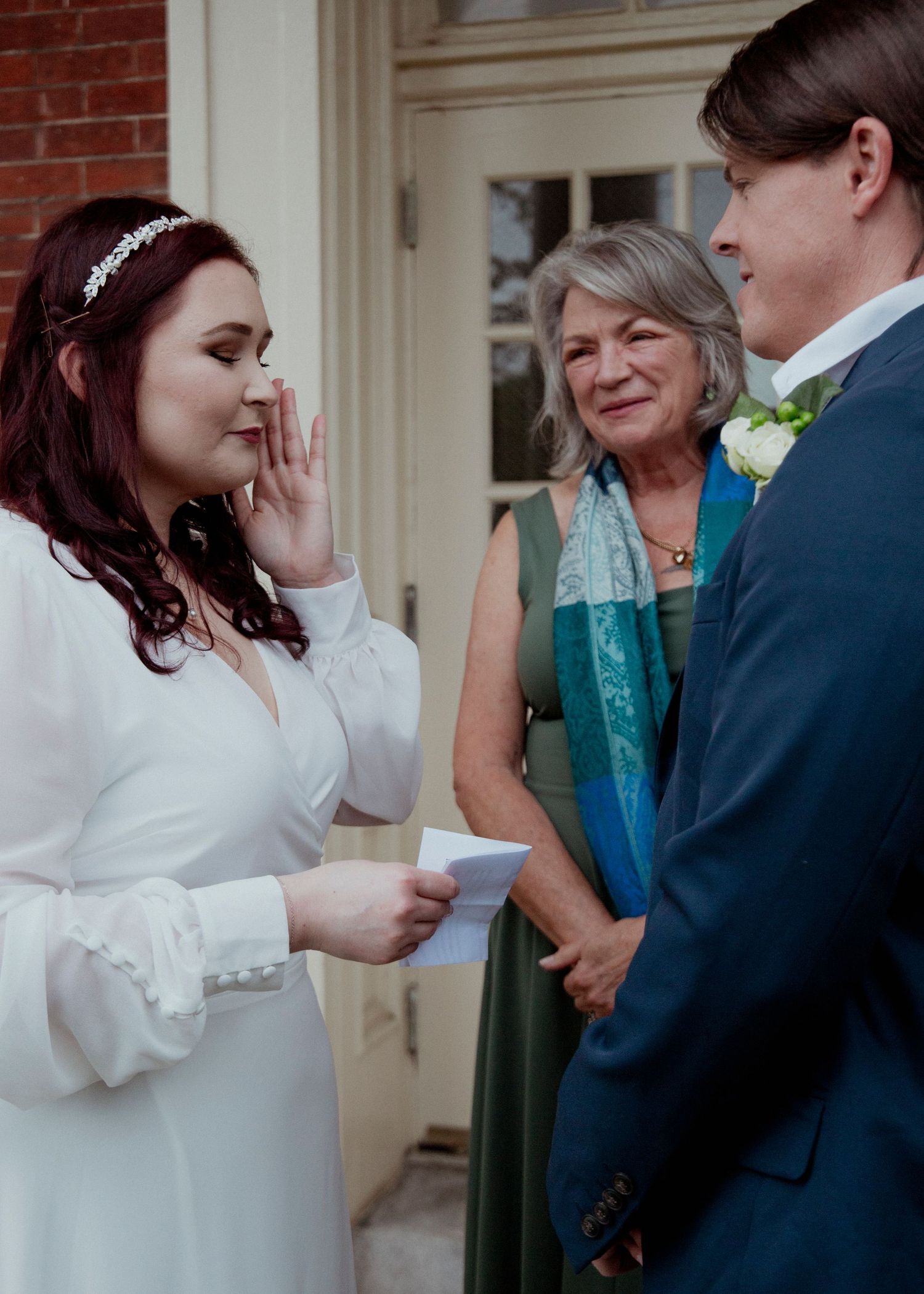 A couple exchanges wedding vows in an intimate ceremony with an officiant wearing a turquoise stole.