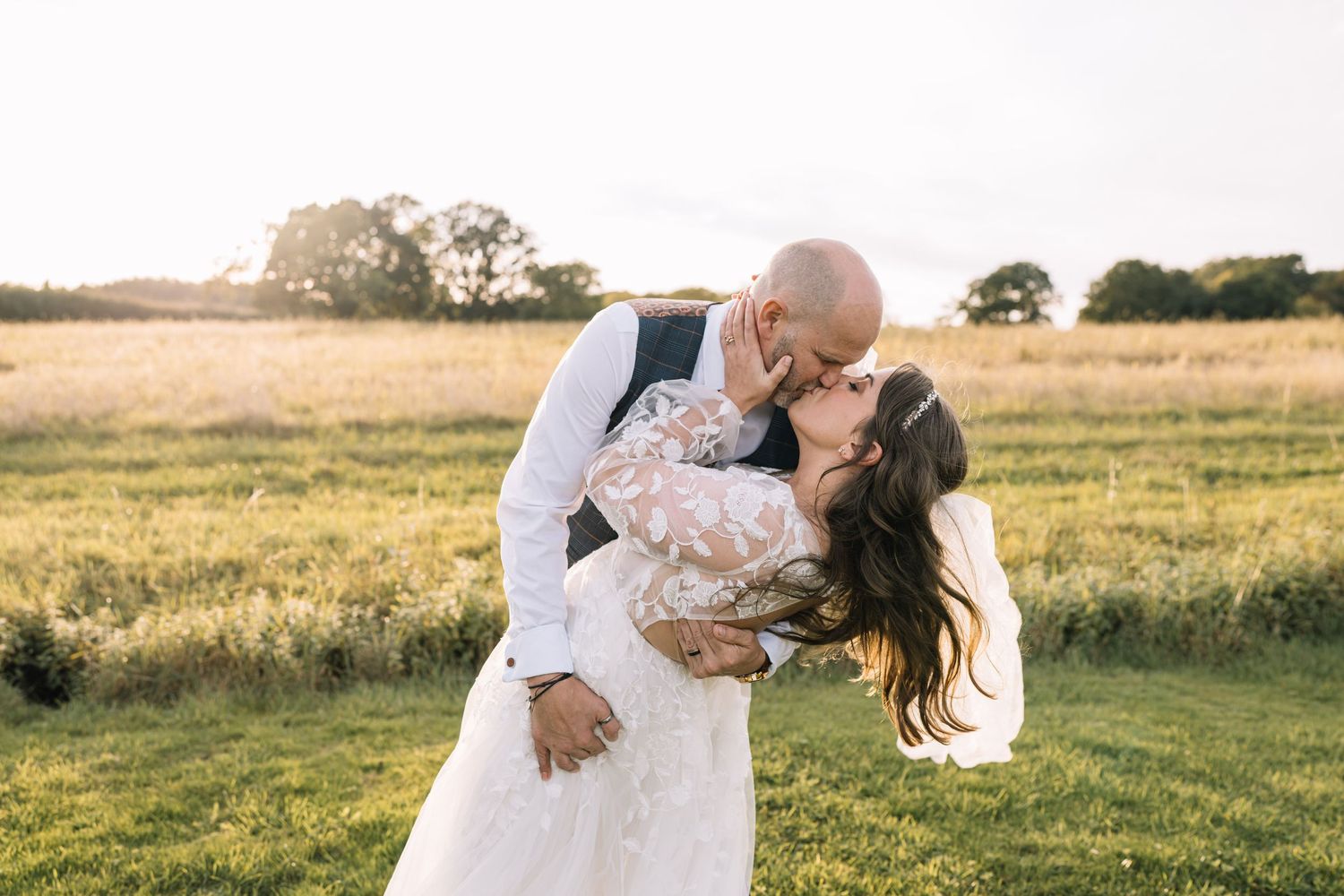 A couple shares a romantic moment in a golden wheat field at sunset during a wedding photo session.