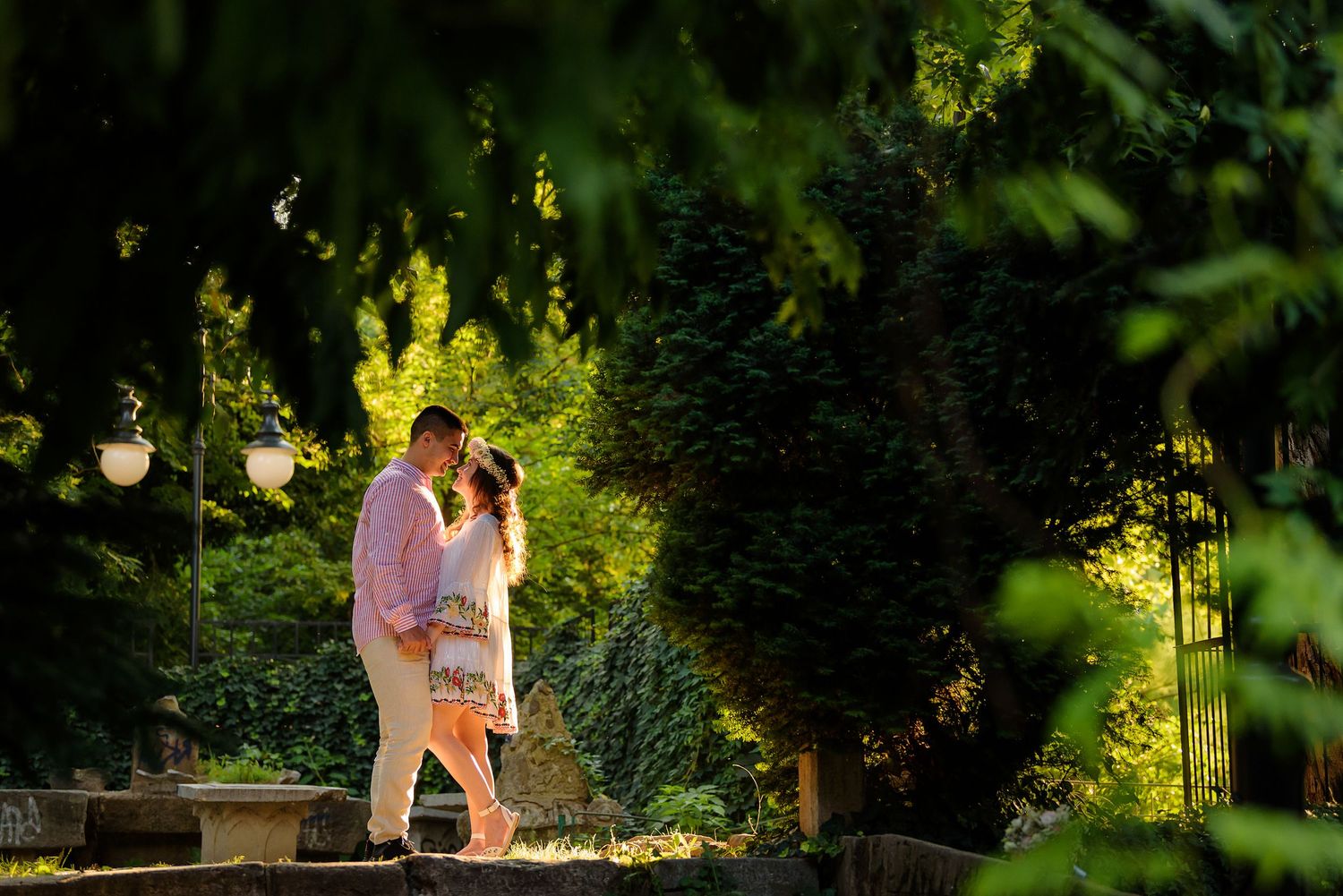 Couple sharing a romantic moment in a beautifully lit garden path during golden hour.