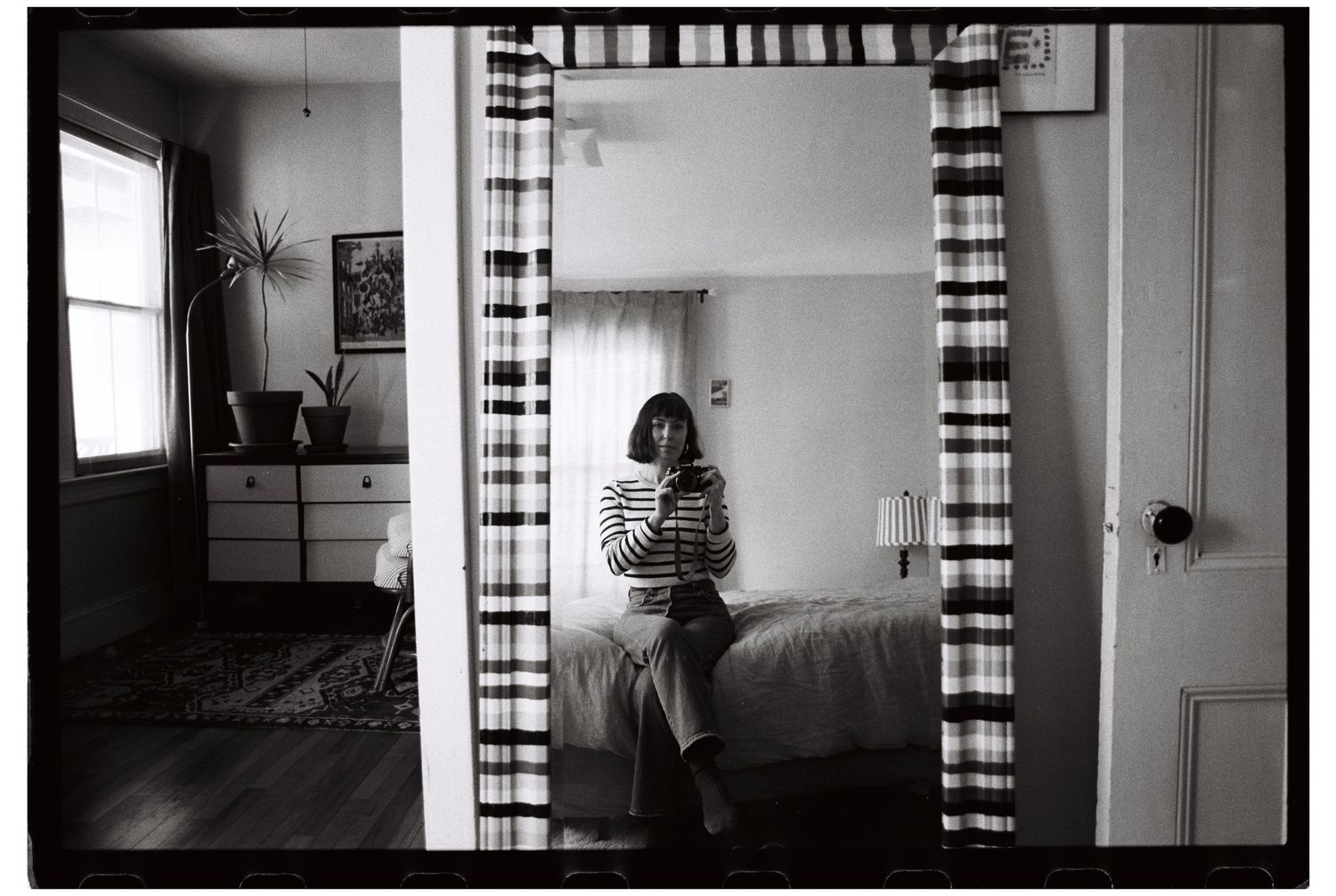 Self portrait of the artist on black and white film at home in the mirror with stripe patterns highlighted throughout the frame.
