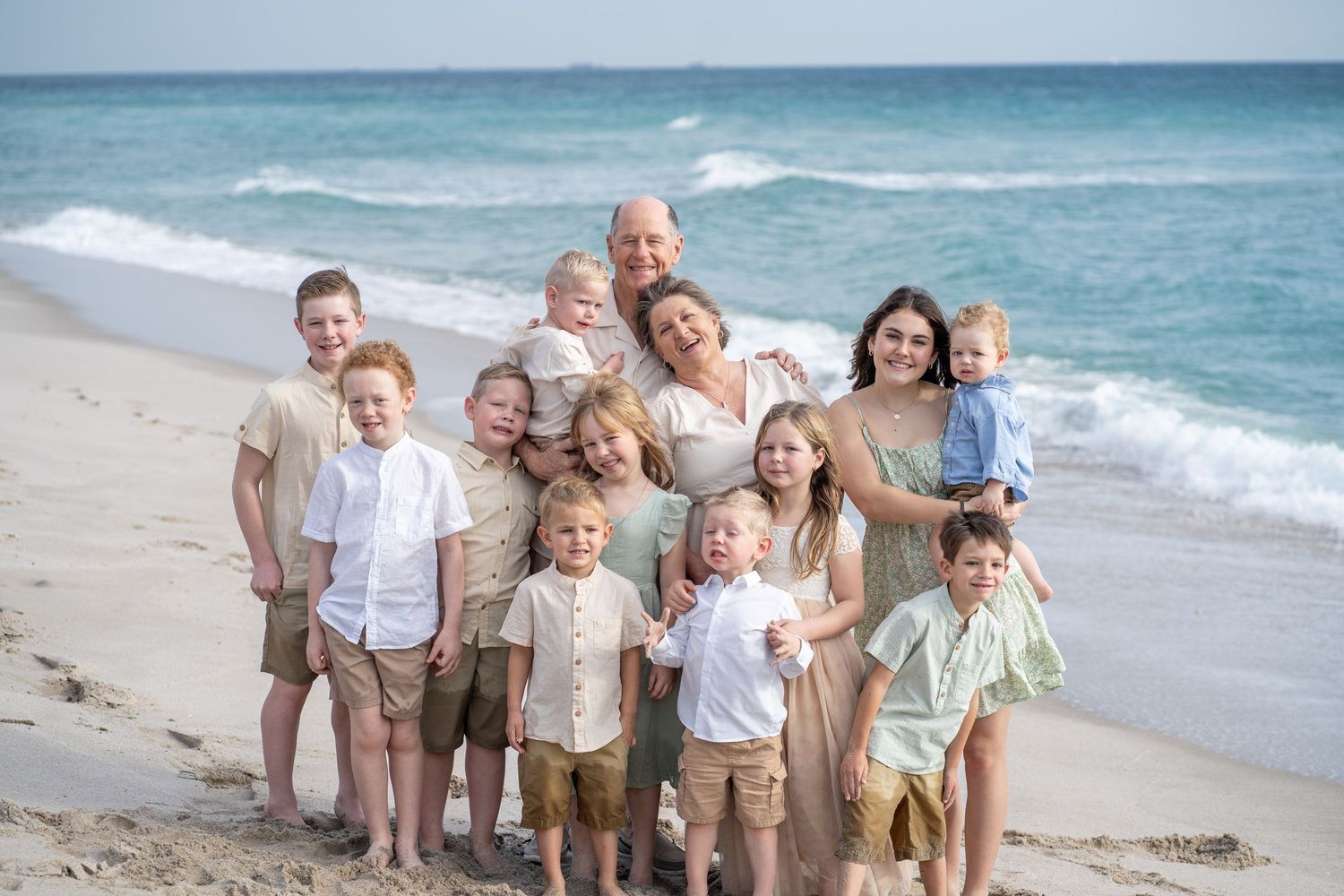 Extended family poses together for group photo on sunny beach.