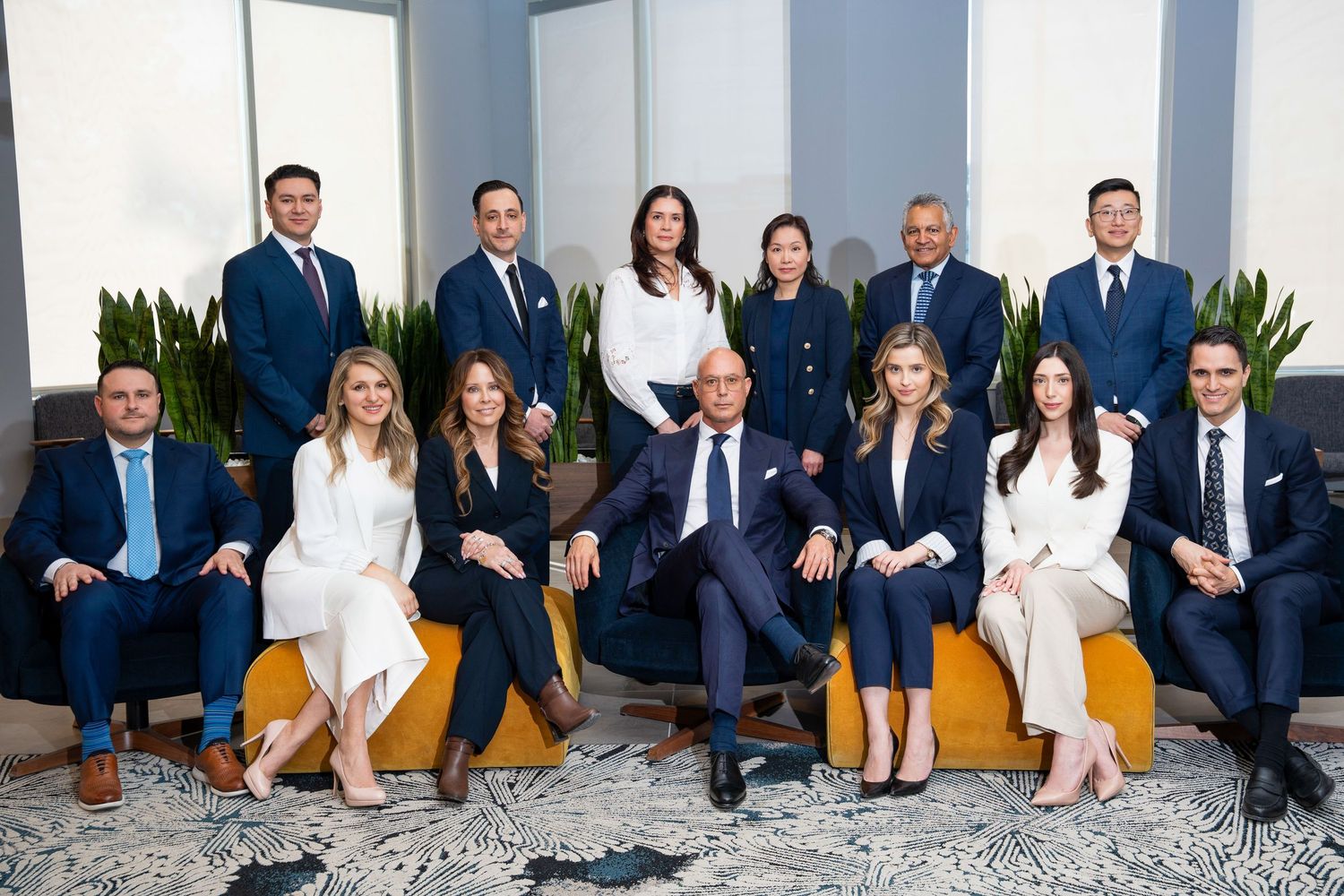 Professional corporate team portrait of 13 business professionals in navy suits posed in a modern office setting.