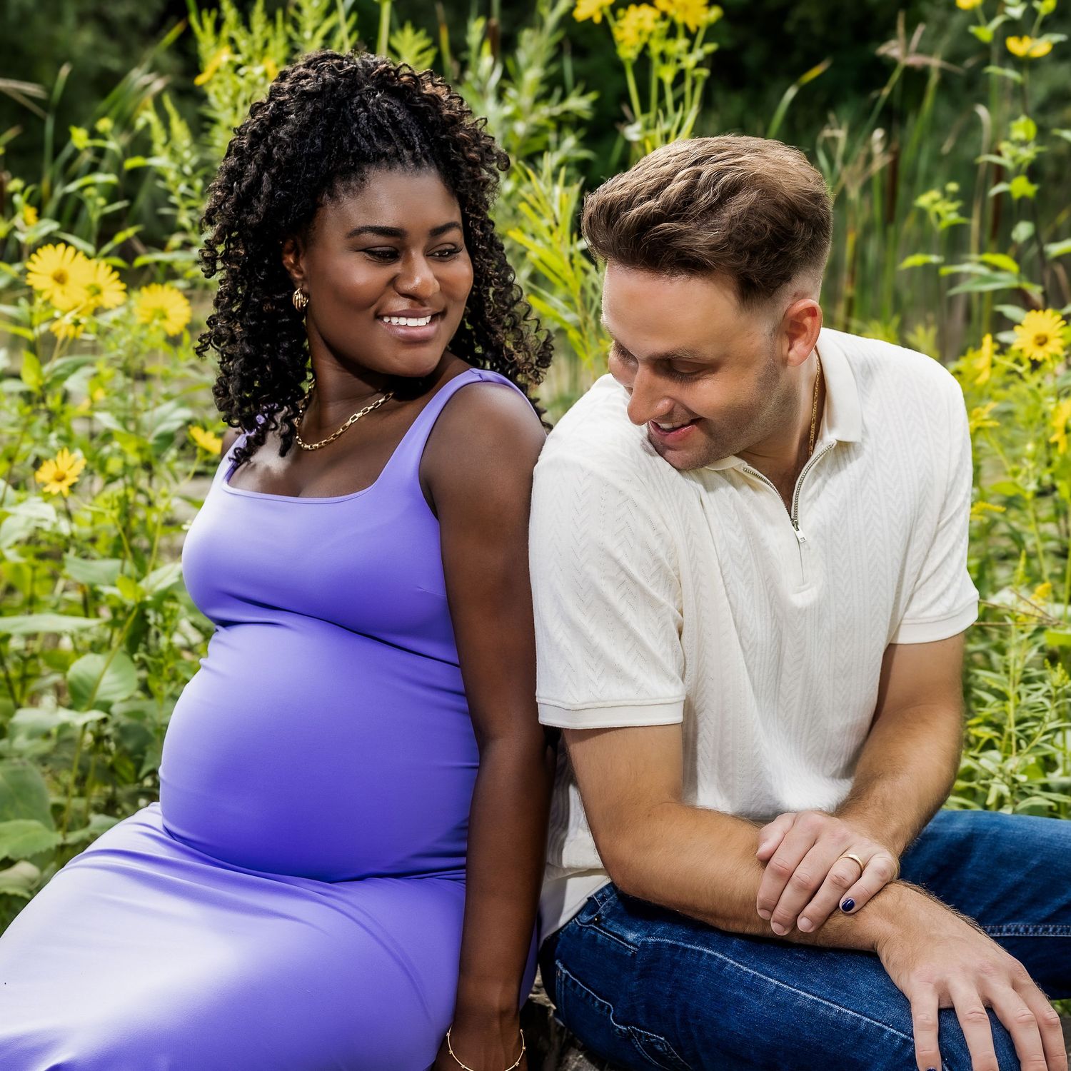 Couple sitting together in a blooming wildflower field sharing intimate moments during a summer photoshoot.
