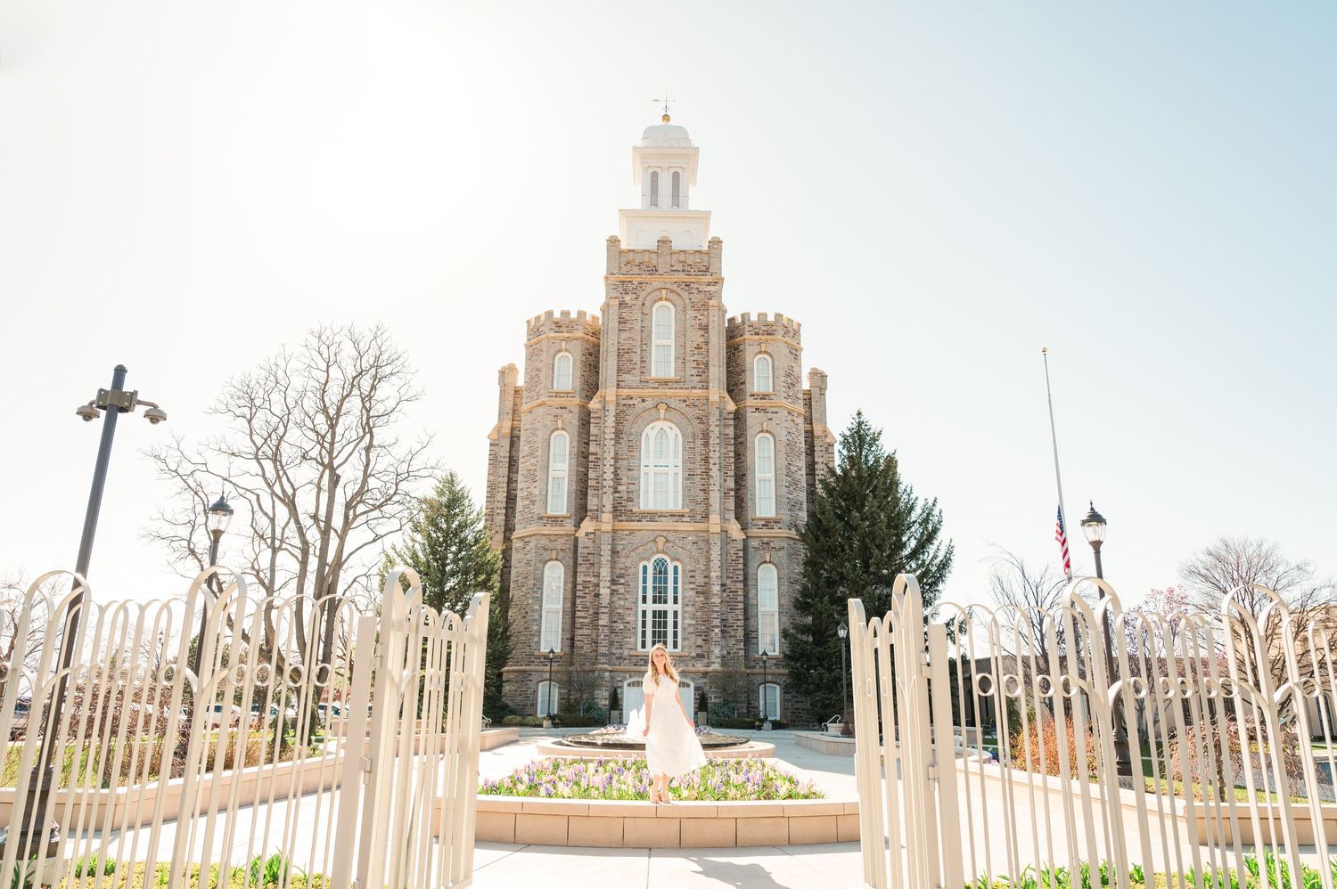 Logan Utah Temple with ornate spires and iron fence photographed against bright sky.