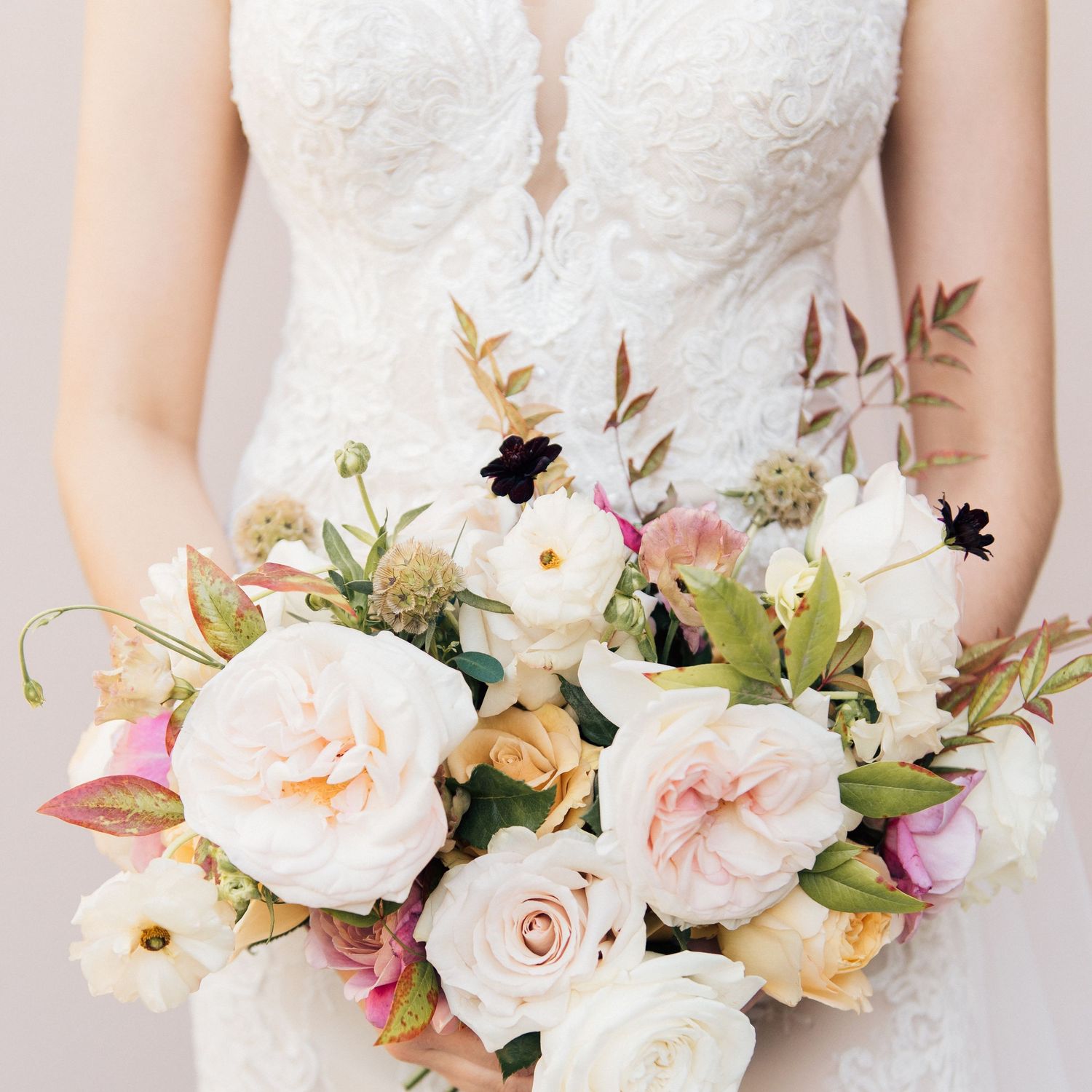 A delicate bridal bouquet features soft pink and white roses with rustic foliage accents.