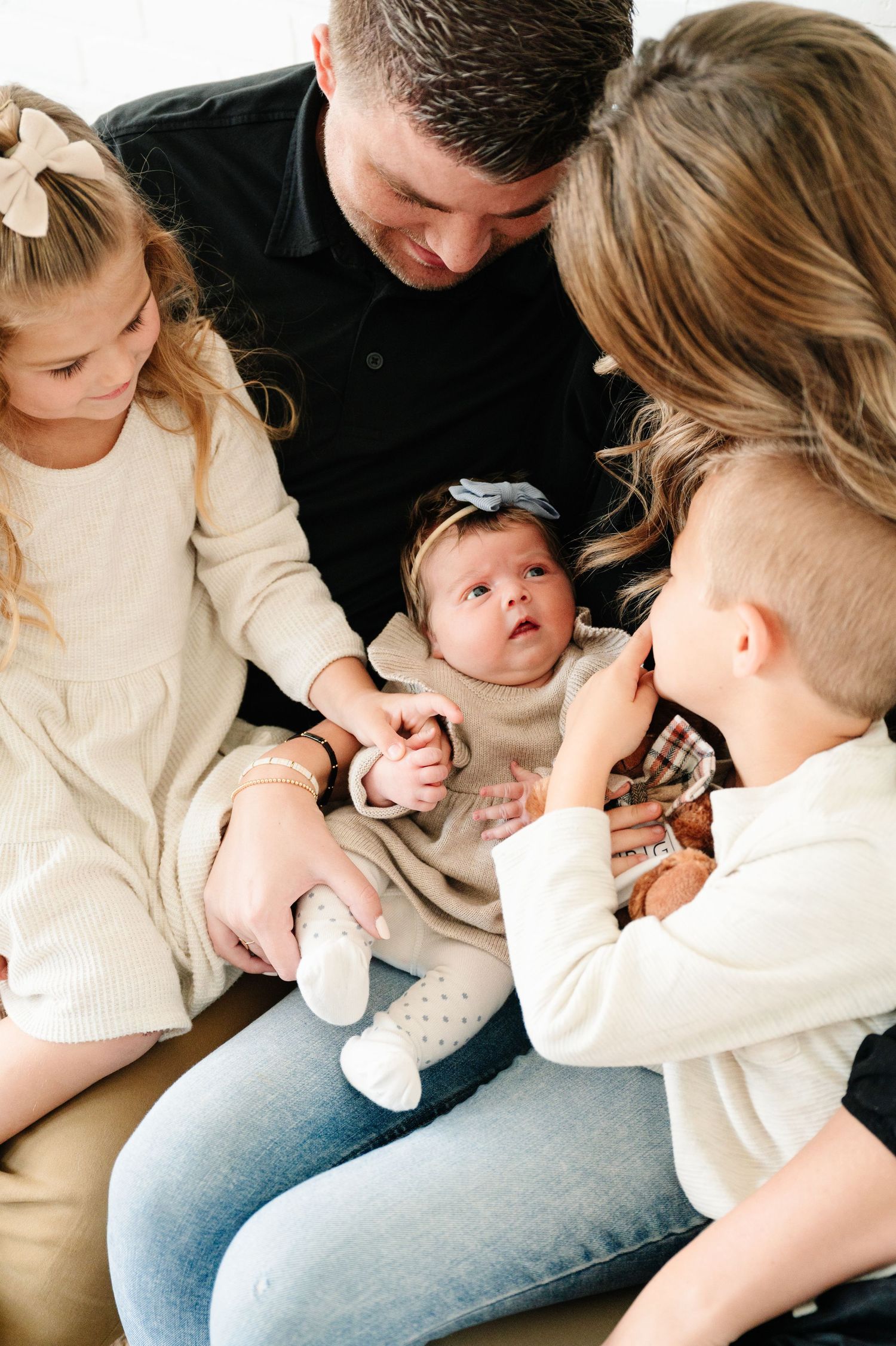 A family gathered closely together around a small baby on a couch.