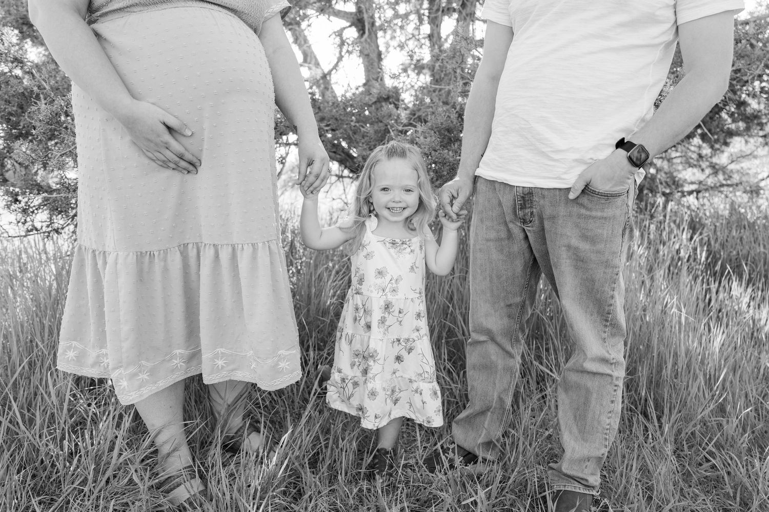 Black and white family portrait taken in a natural outdoor setting with tall grass.