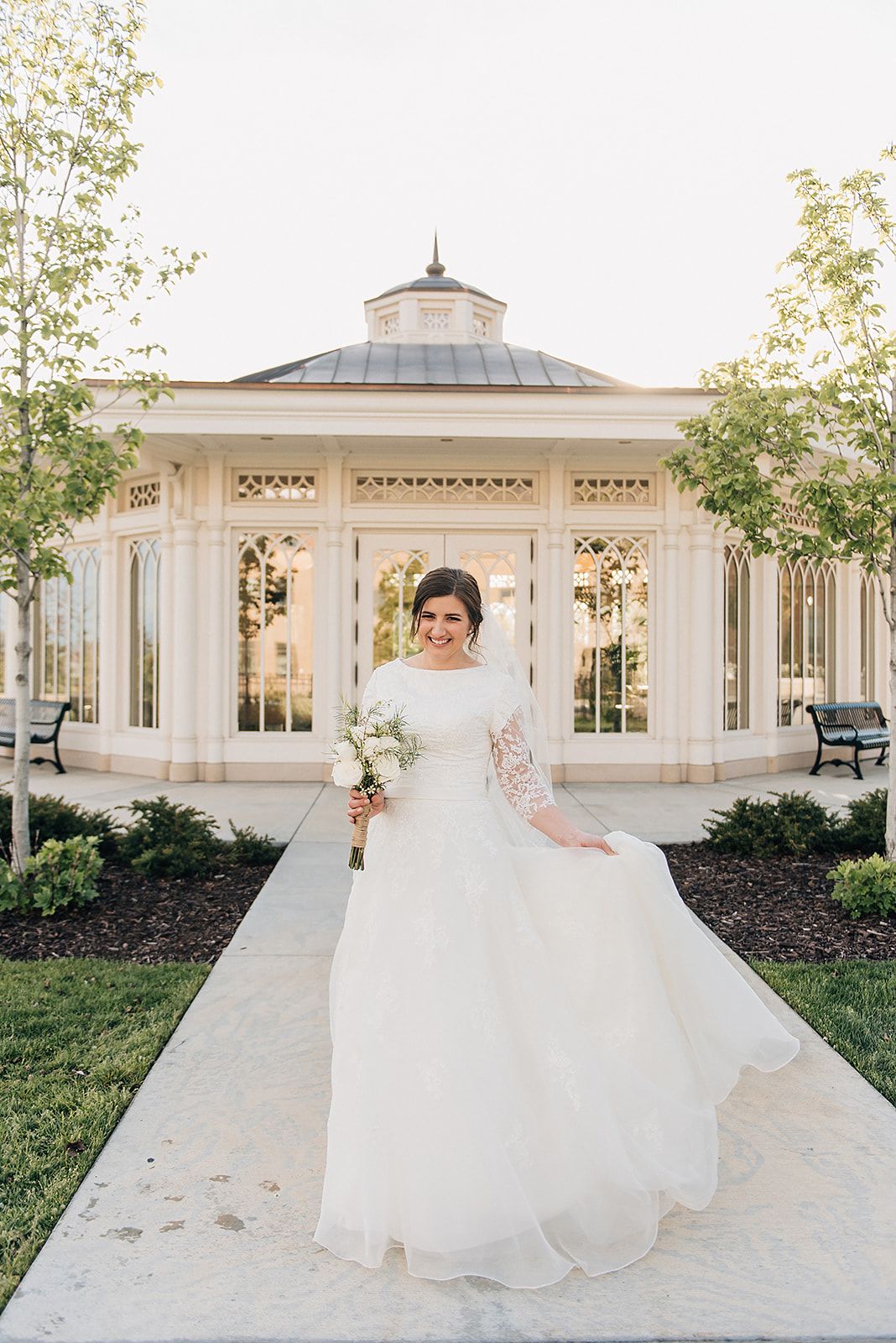 Elegant bridal portrait in front of a white gazebo surrounded by manicured gardens.