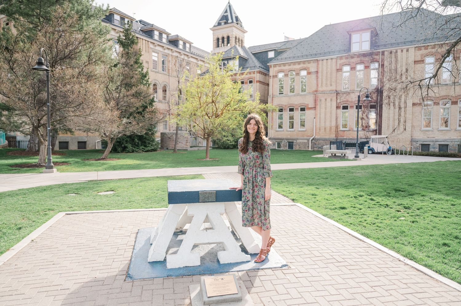 College student standing on architectural detail in front of historic university building on spring day.
