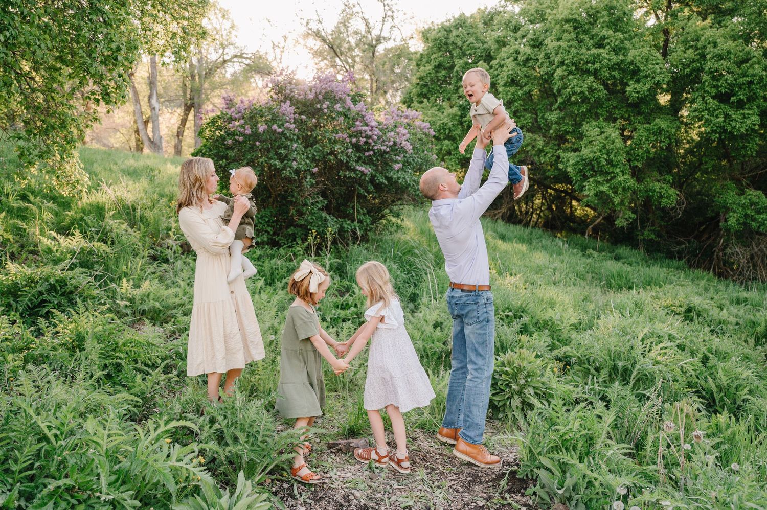 A family walks together through a lush green garden path on a sunny summer afternoon.