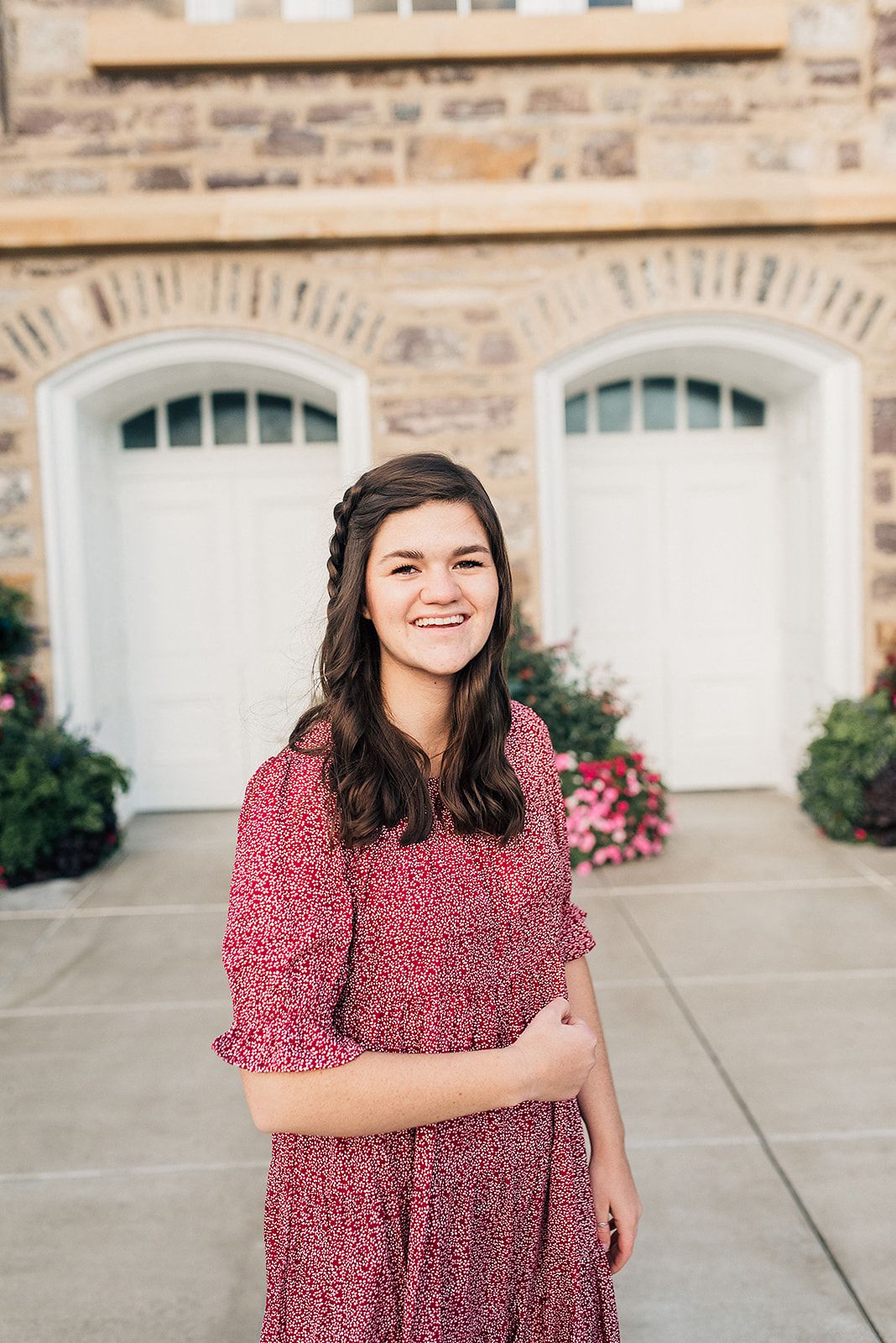 Outdoor portrait in front of stone garage doors with someone wearing a red patterned dress.