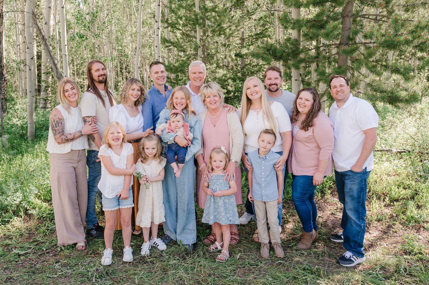Extended family gathering outdoors with multiple generations dressed in coordinated pastel colors.