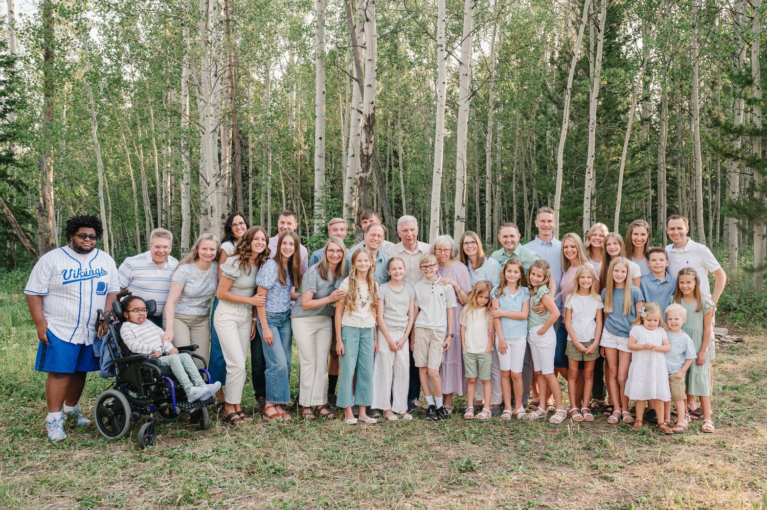 A large group gathering poses together in a beautiful aspen grove.