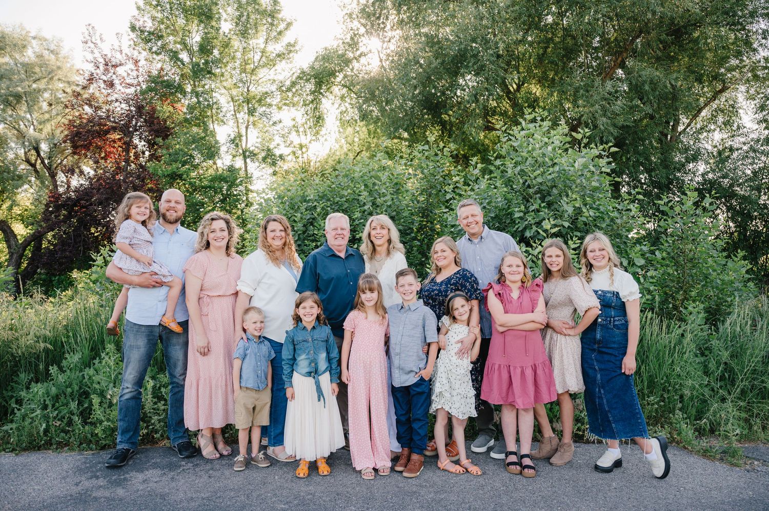 Extended family gathers for outdoor portrait session in coordinated pink and blue outfits.