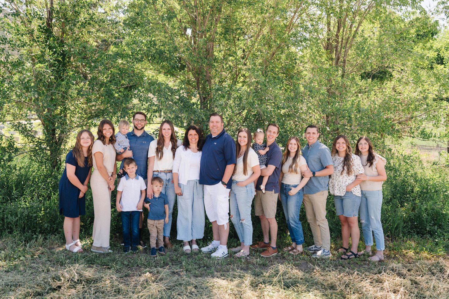A large extended family group photo outdoors against a natural green background.