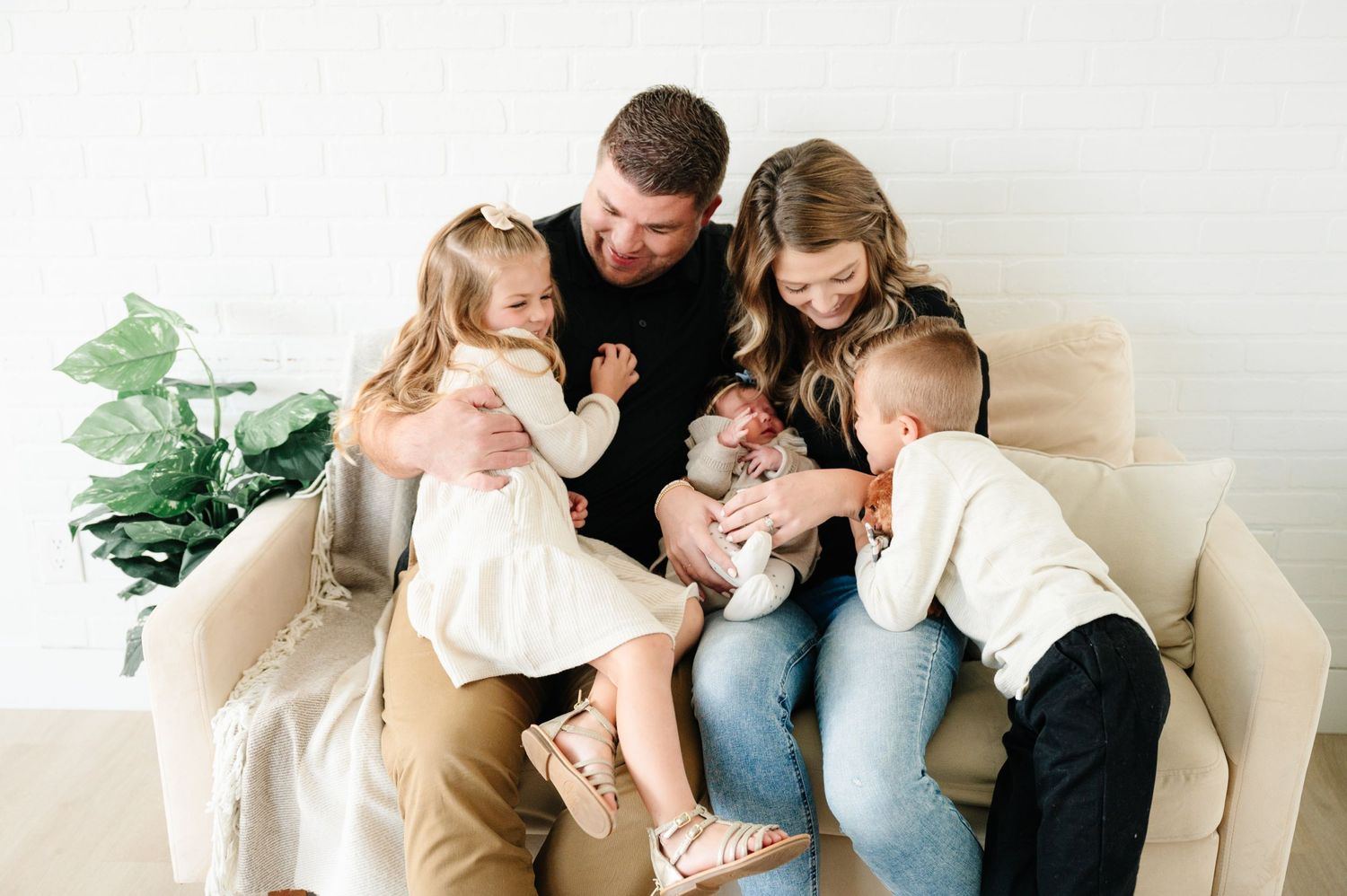 An intimate family moment captured on a white couch with young children.