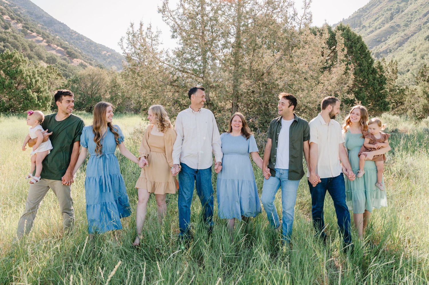 A group poses together in coordinated outfits against a mountainous backdrop.