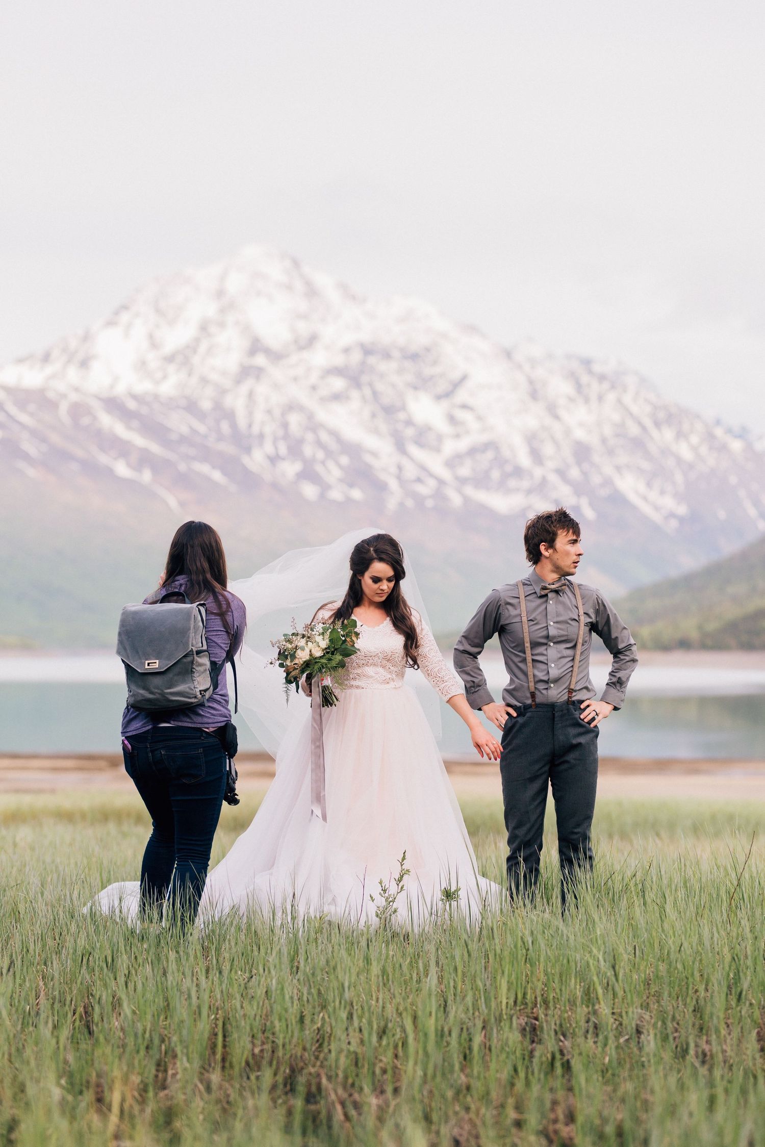 Wedding photoshoot in front of snow-capped mountains with a scenic lake backdrop.