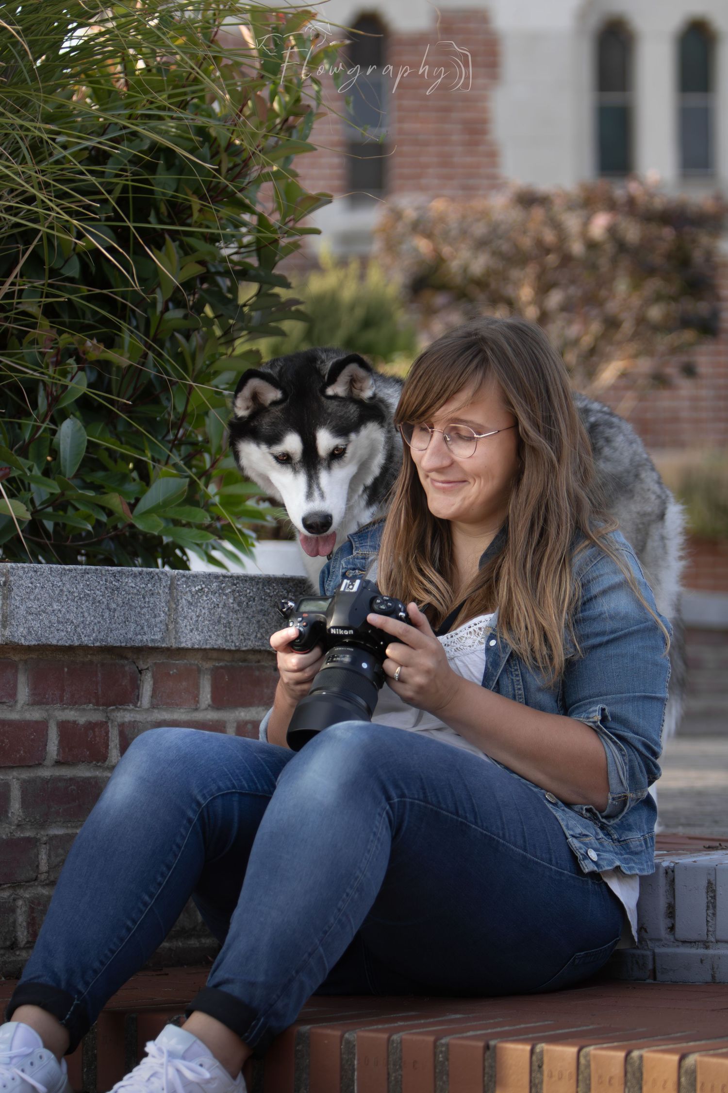 Portait d'une photographe avec son chien husky regardant l'appareil photo de la jeune femme
