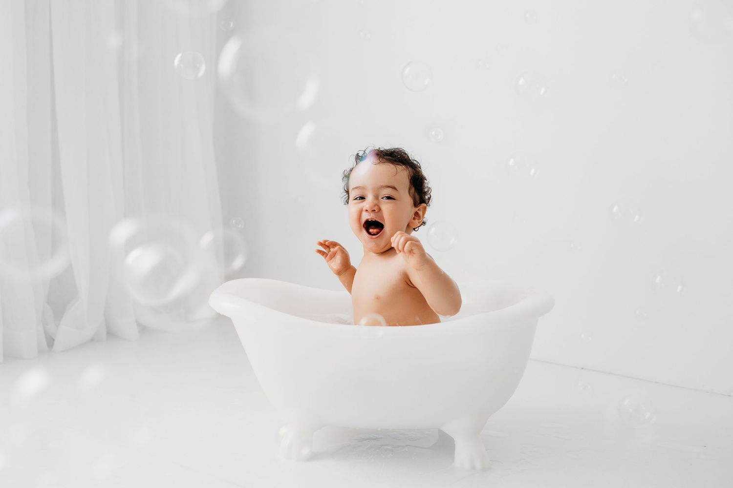 Little boy laughing at bubbles at his cake smash birthday photography session in Santa Fe. 1st bday photos in Los Alamos