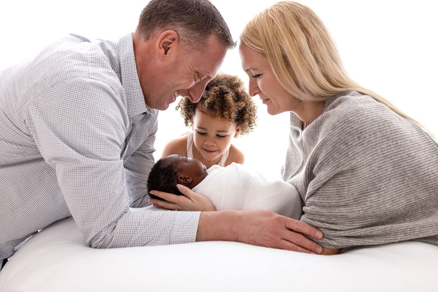 Family looking down at baby in swaddle. Toddler sister and newborn baby. Newborn photos in Santa Fe.