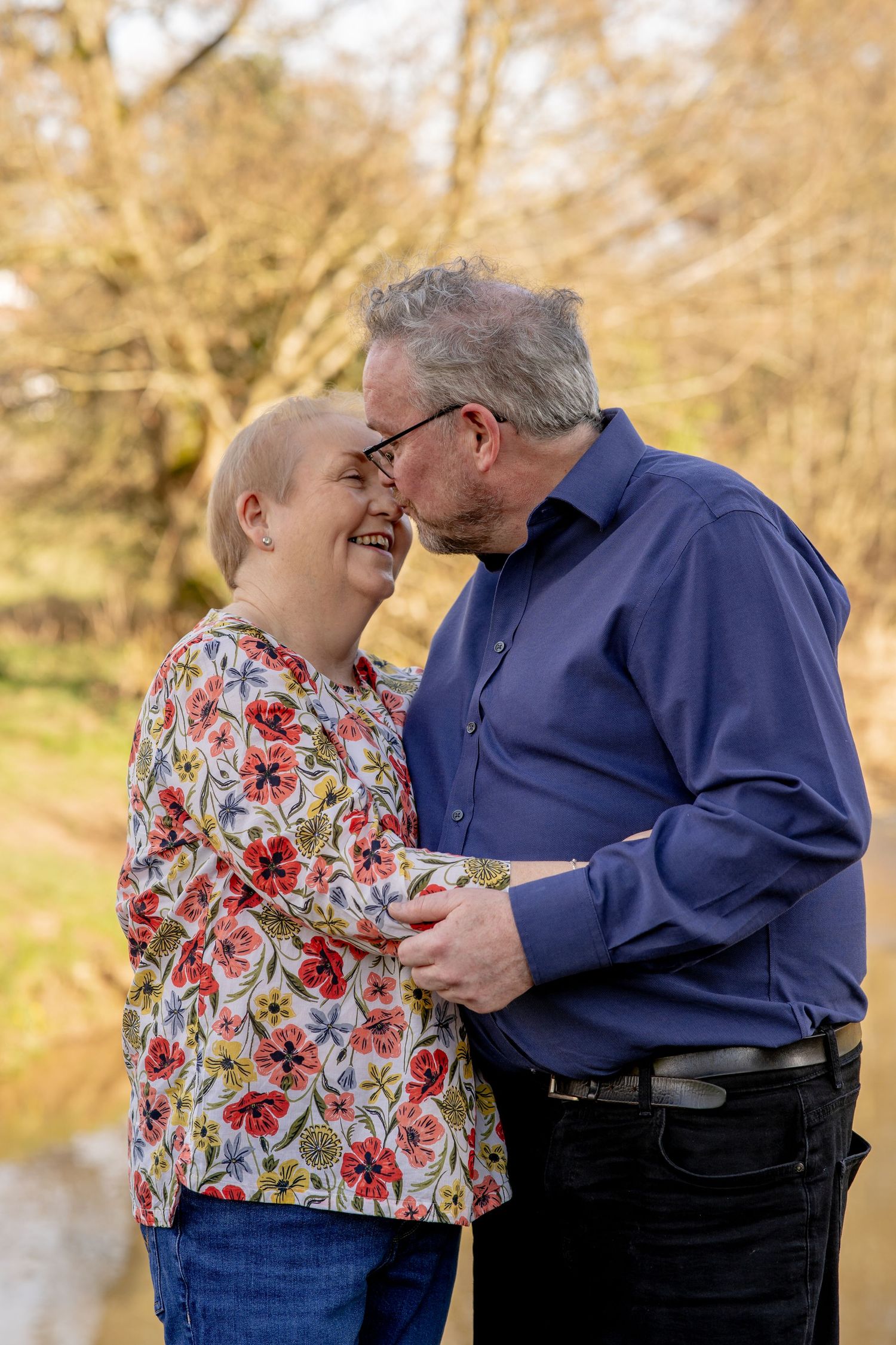 Senior couple sharing an intimate moment outdoors in autumn, smiling and embracing together.