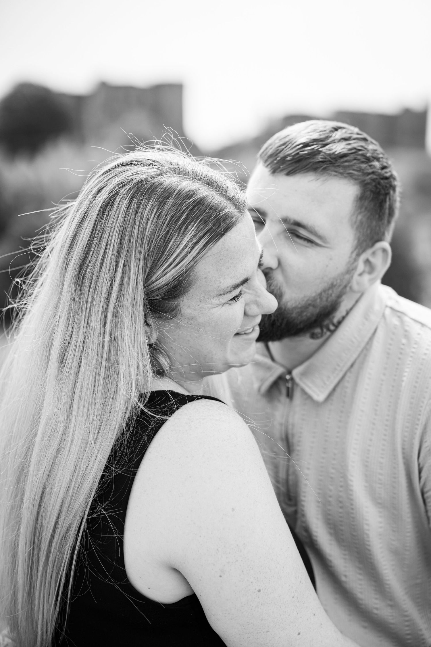 A romantic black and white portrait of a couple sharing an intimate moment outdoors.
