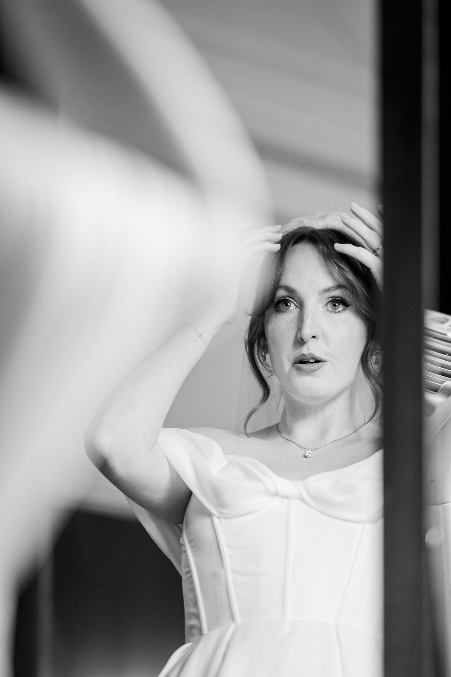 Black and white portrait of someone in a white dress leaning by a window, creating a soft romantic atmosphere.