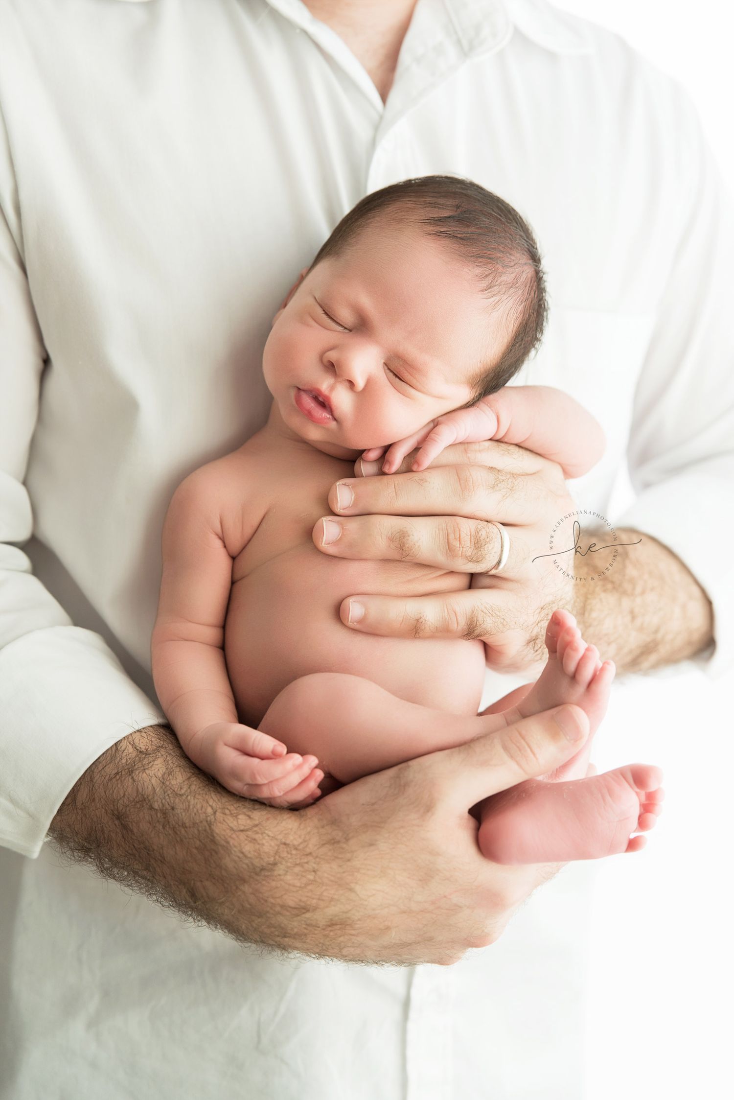Newborn baby sleeping peacefully while being cradled in parent's hands.