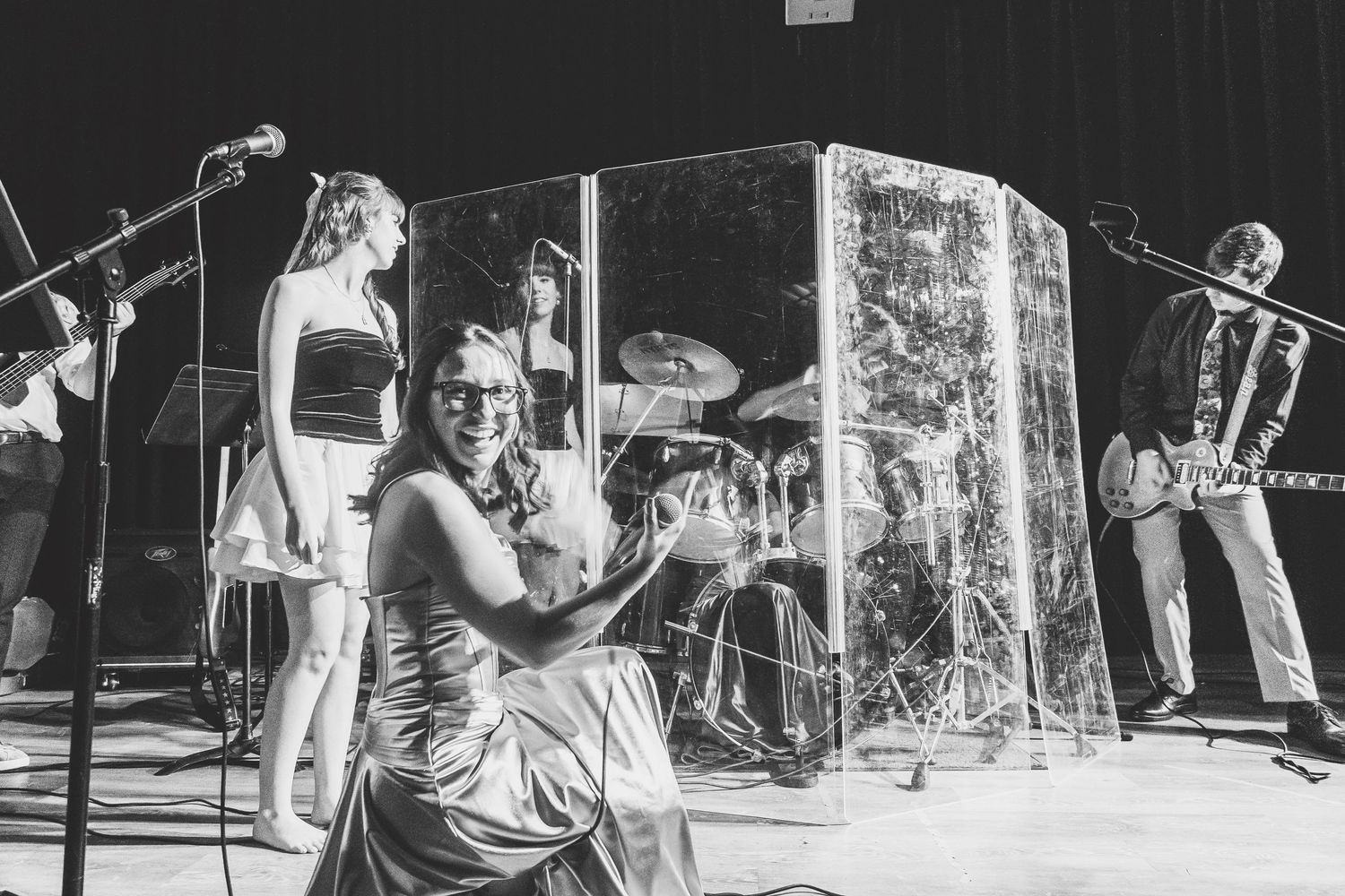 Live band performance with female vocalist smiling on stage in black and white.