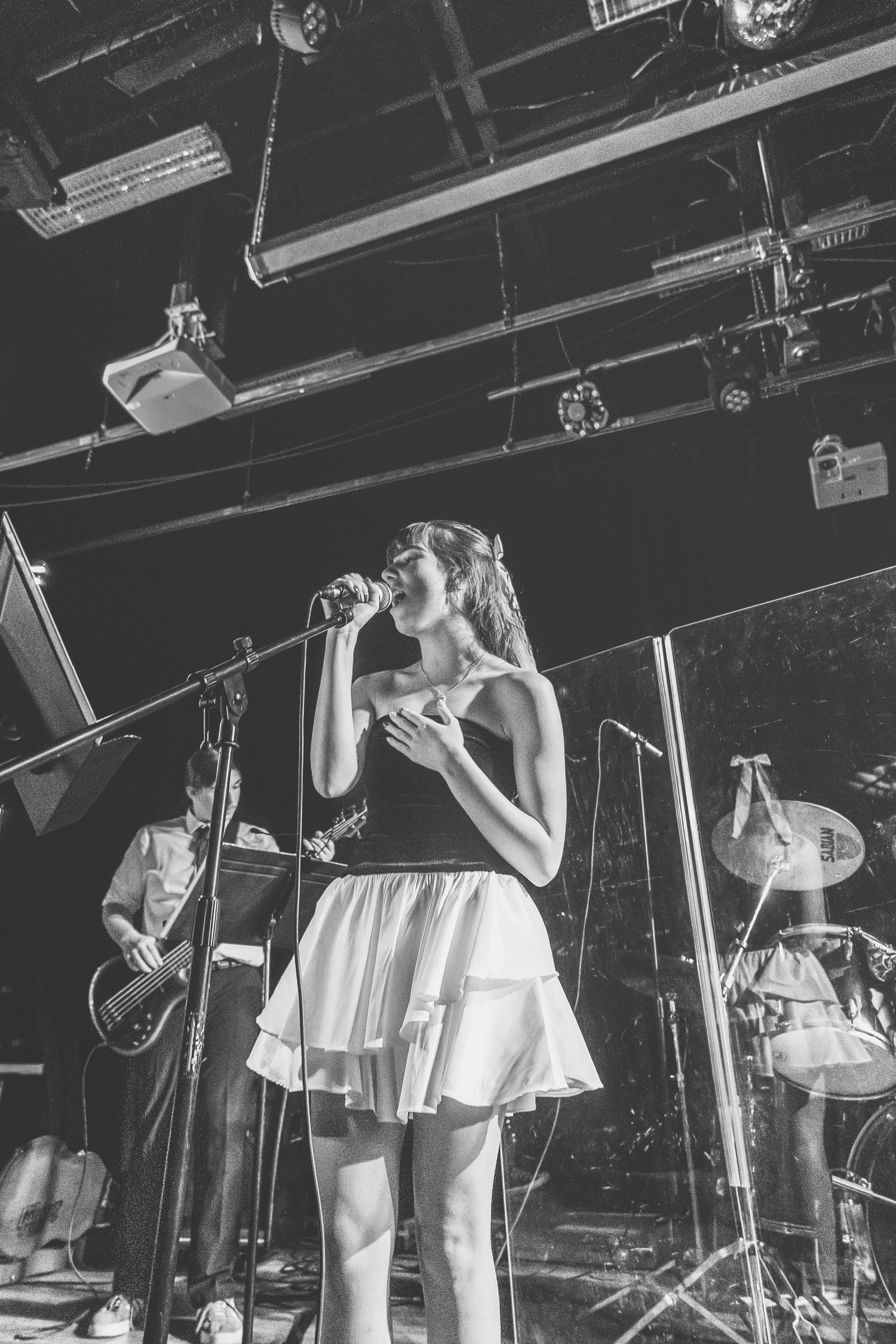 Female singer performing on stage with band in black and white concert photo.