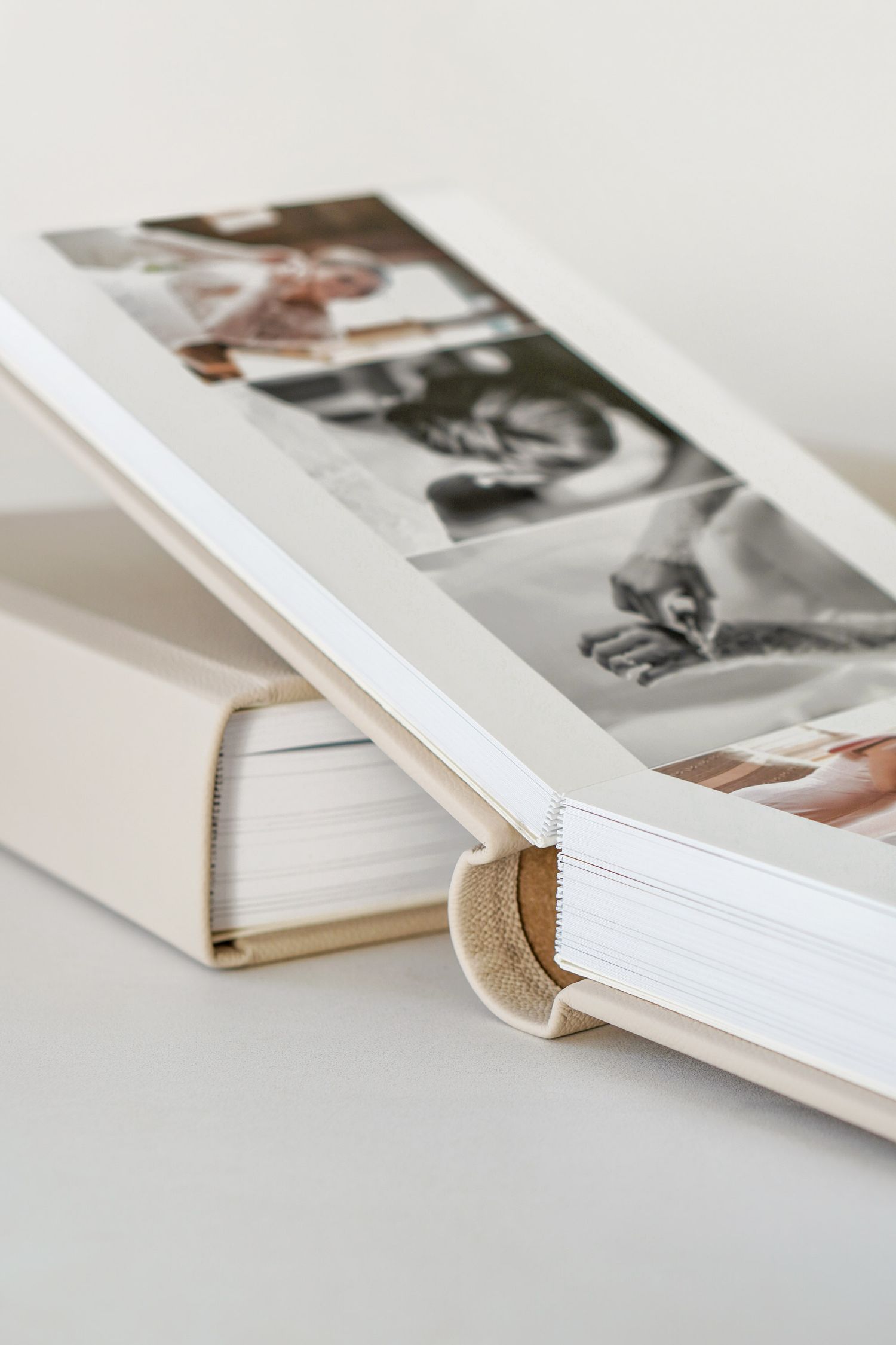 Close-up view of photo albums with black and white images visible on top, stacked on a light neutral surface.