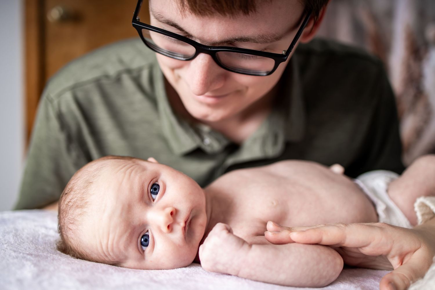 A close up view of a baby with bright eyes and rosy cheeks lying on a soft surface. newborn photographer in RVA. Richmond, VA photographer