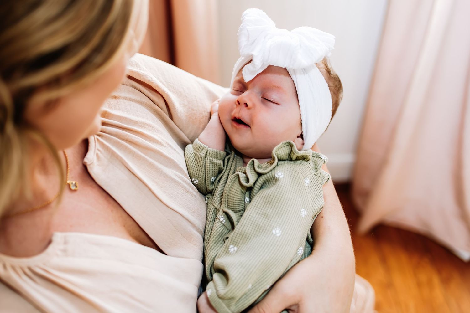 Candid shots of mother and newborn baby bonding on cream colored bed during lifestyle photography session.