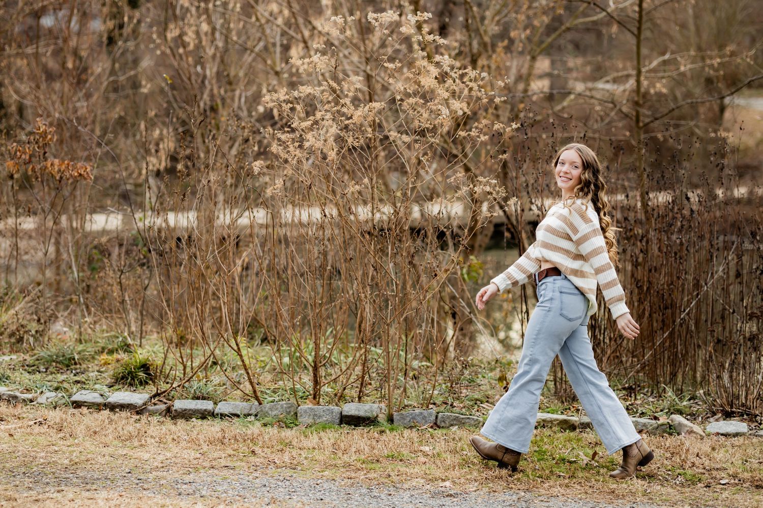 A person in a white dress twirls joyfully in a rustic outdoor setting during autumn.