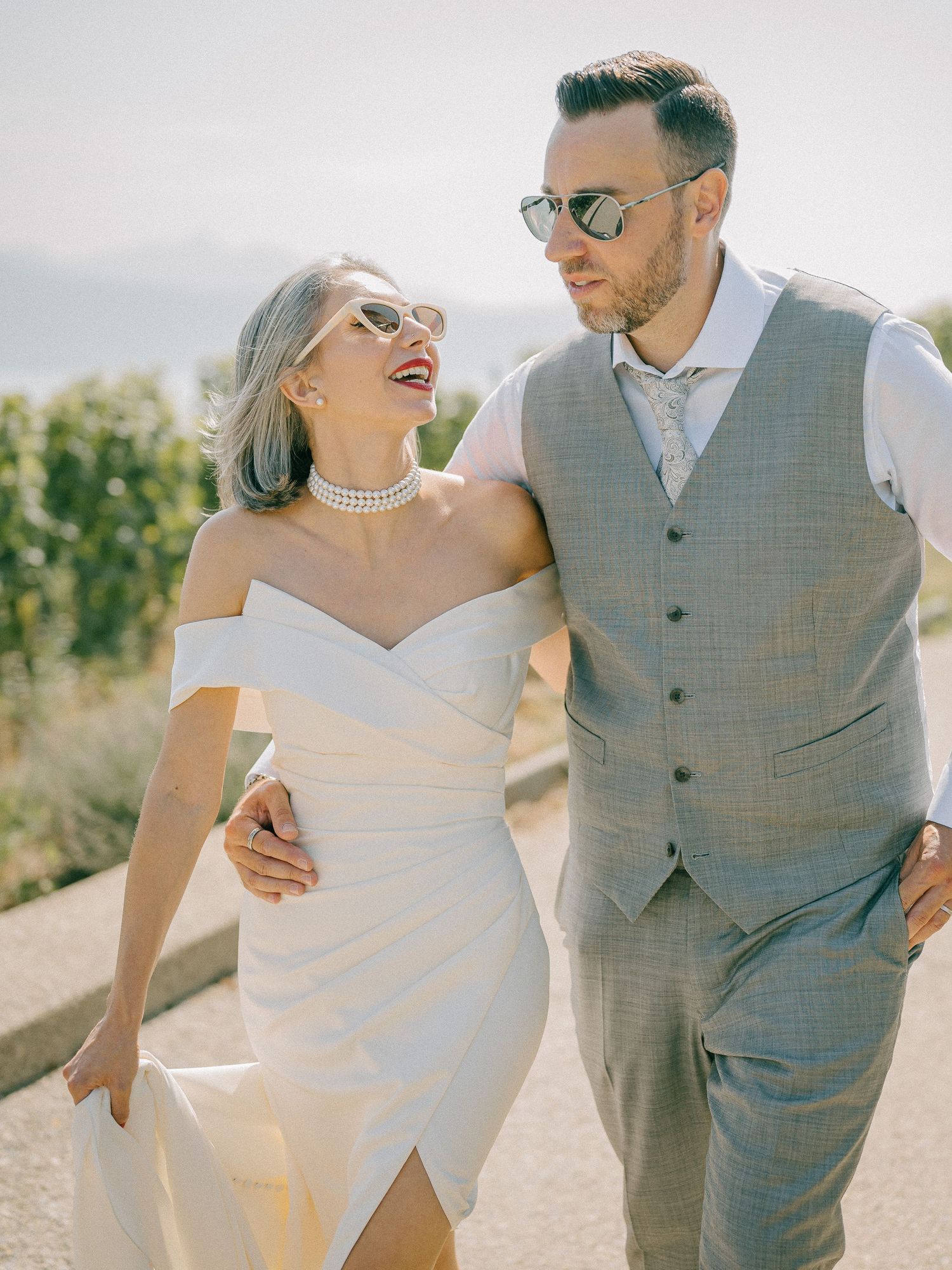 Joyful wedding couple sharing a laugh outdoors with mountain scenery.