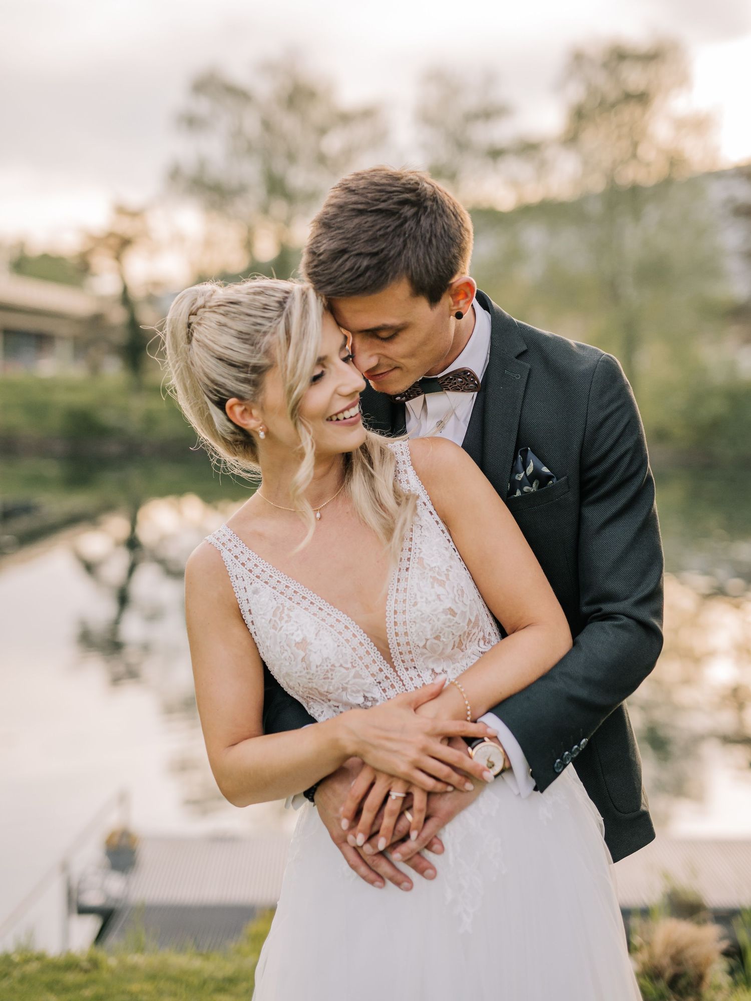 A romantic wedding couple embraces during golden hour in an outdoor garden setting.