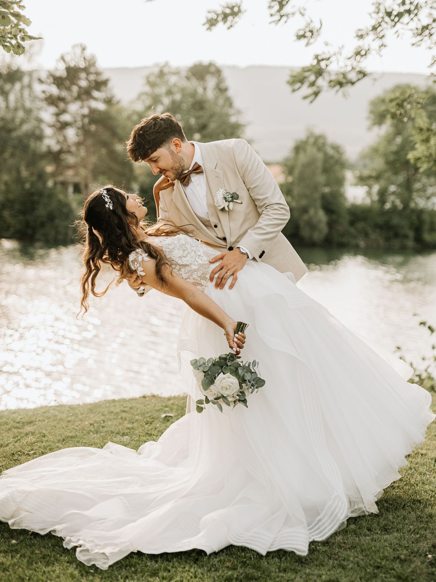 Romantic wedding couple dancing on grass with flowing white dress.