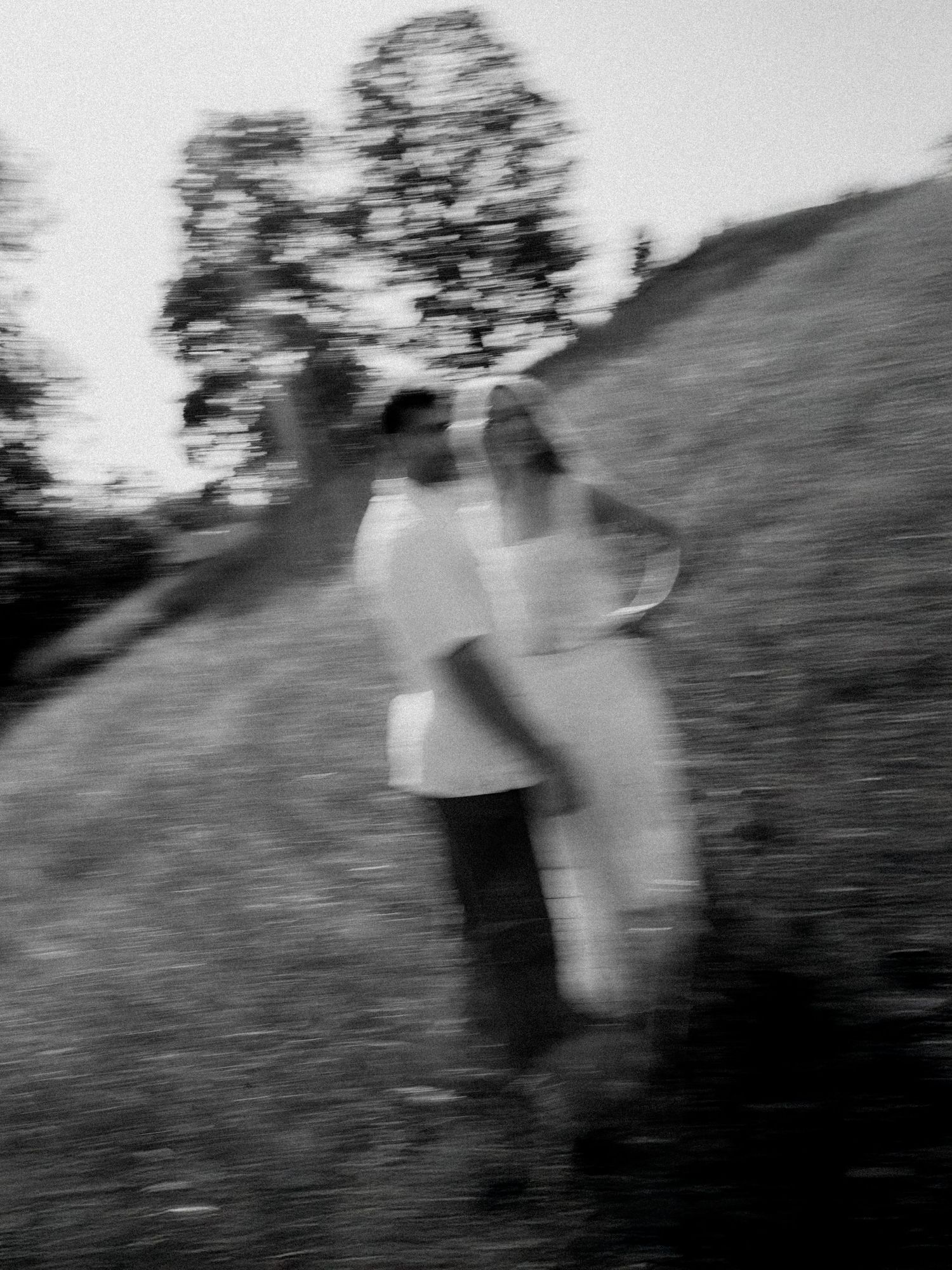 Black and white motion blur photograph of two people dancing in nature.