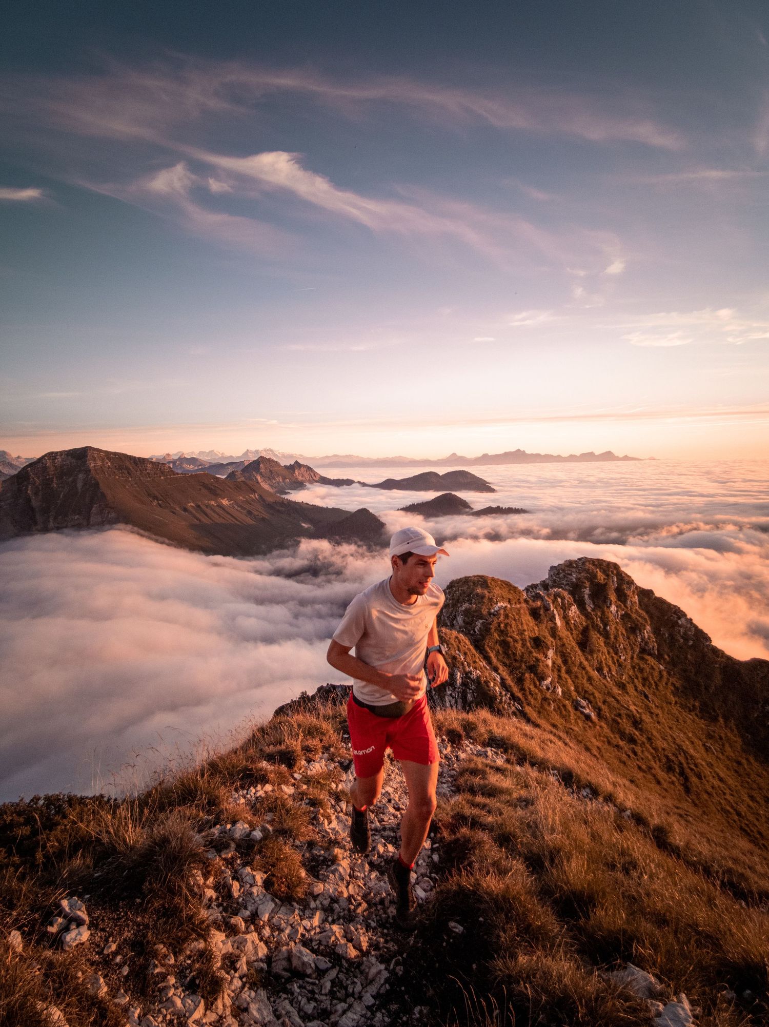 Stunning mountain ridge above a sea of clouds during golden hour with warm sunset colors.