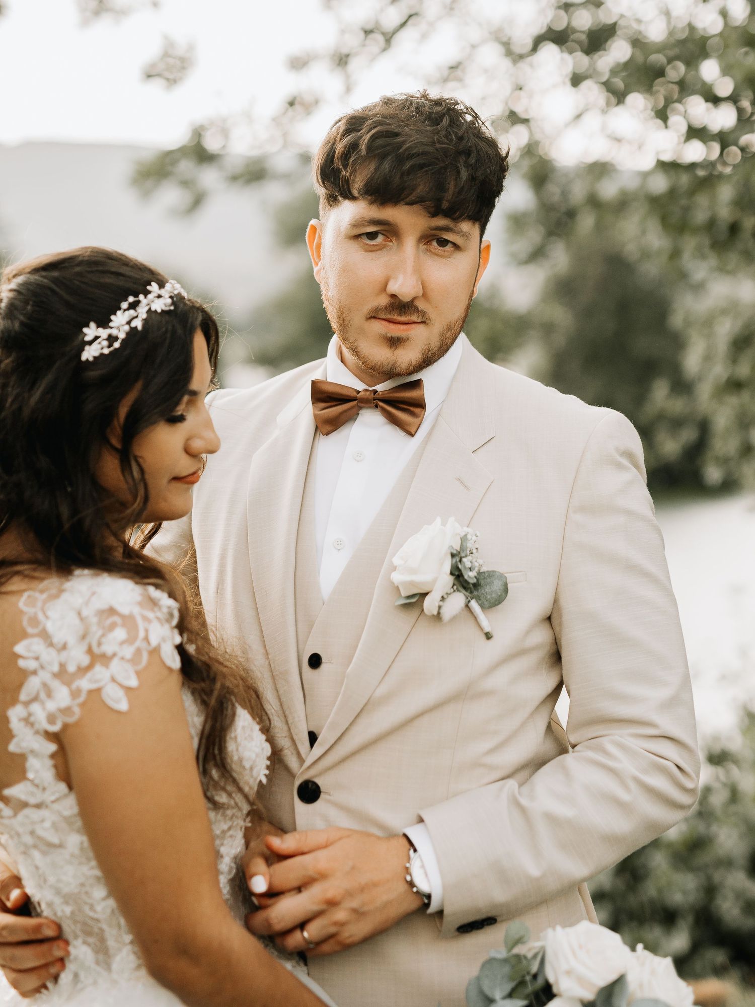 Elegant wedding couple in white attire sharing intimate moment outdoors.