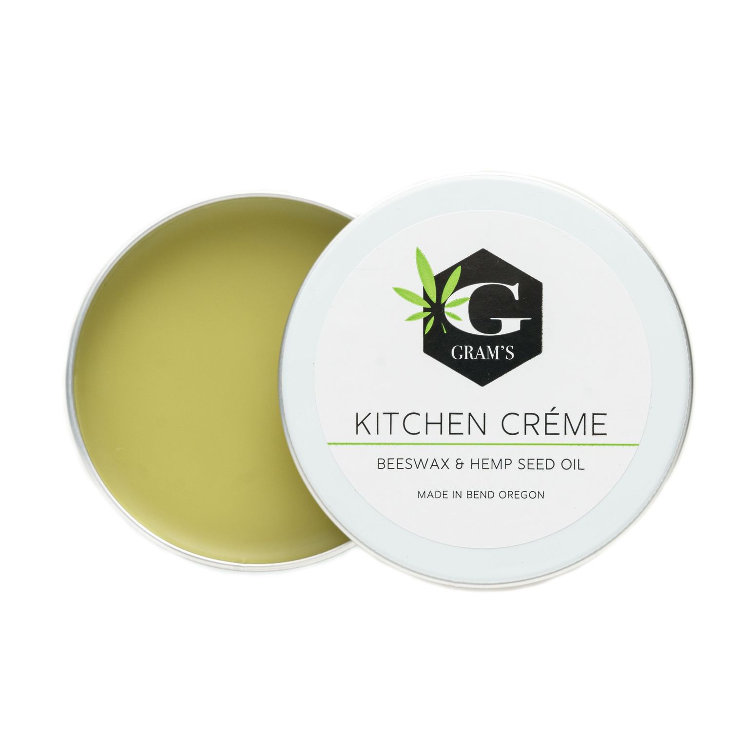 Open jar of Gram's Kitchen Creme showing green beeswax and hemp oil blend.