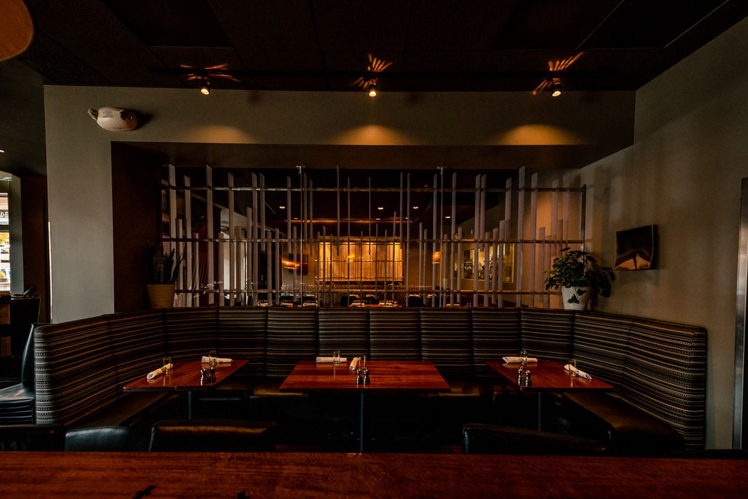 Modern restaurant dining area with red booth seating and industrial-style metal decor elements.