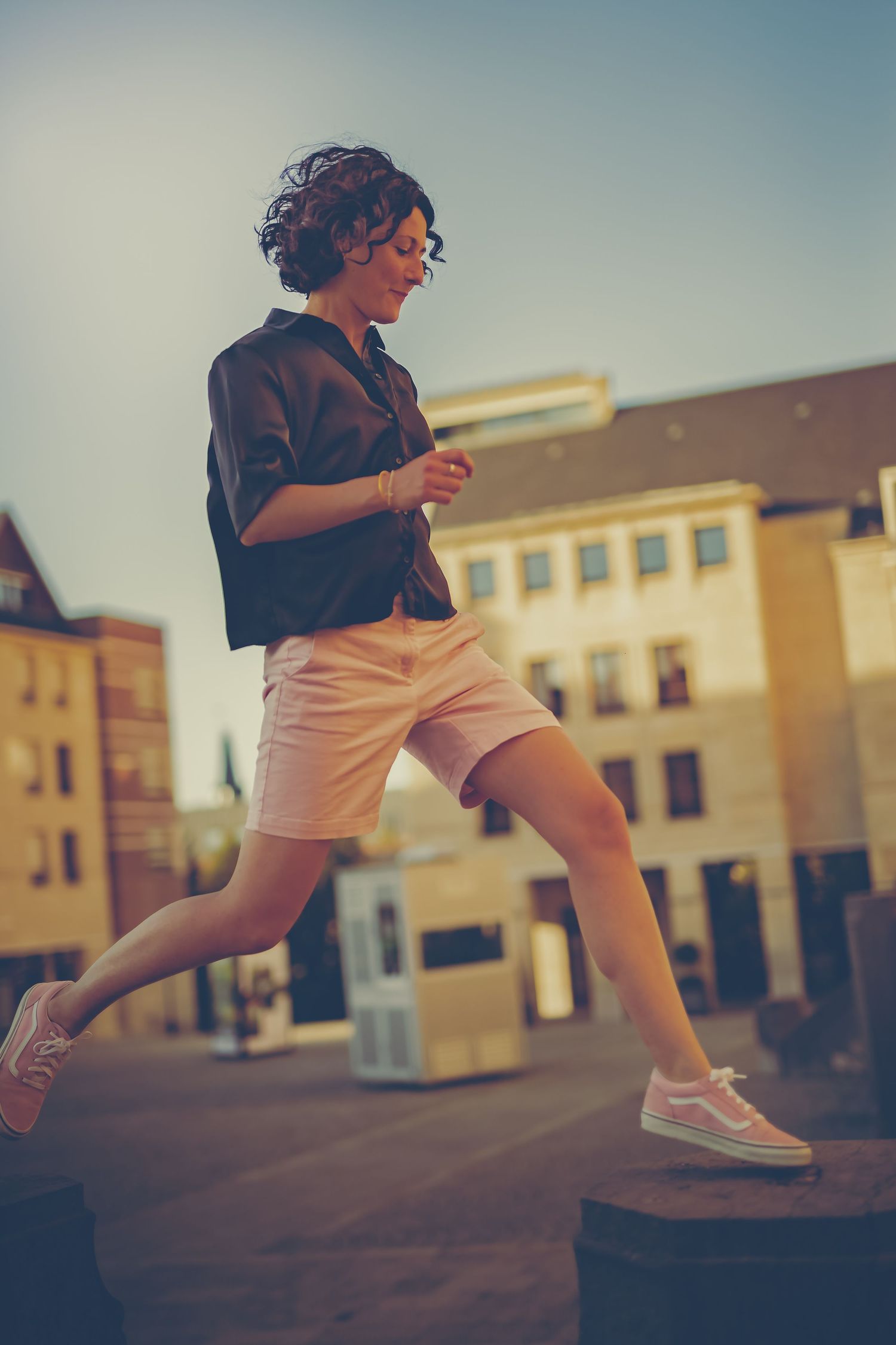 Runner leaps over stairs in urban setting wearing black jacket and white shorts with retro vintage film style colors.