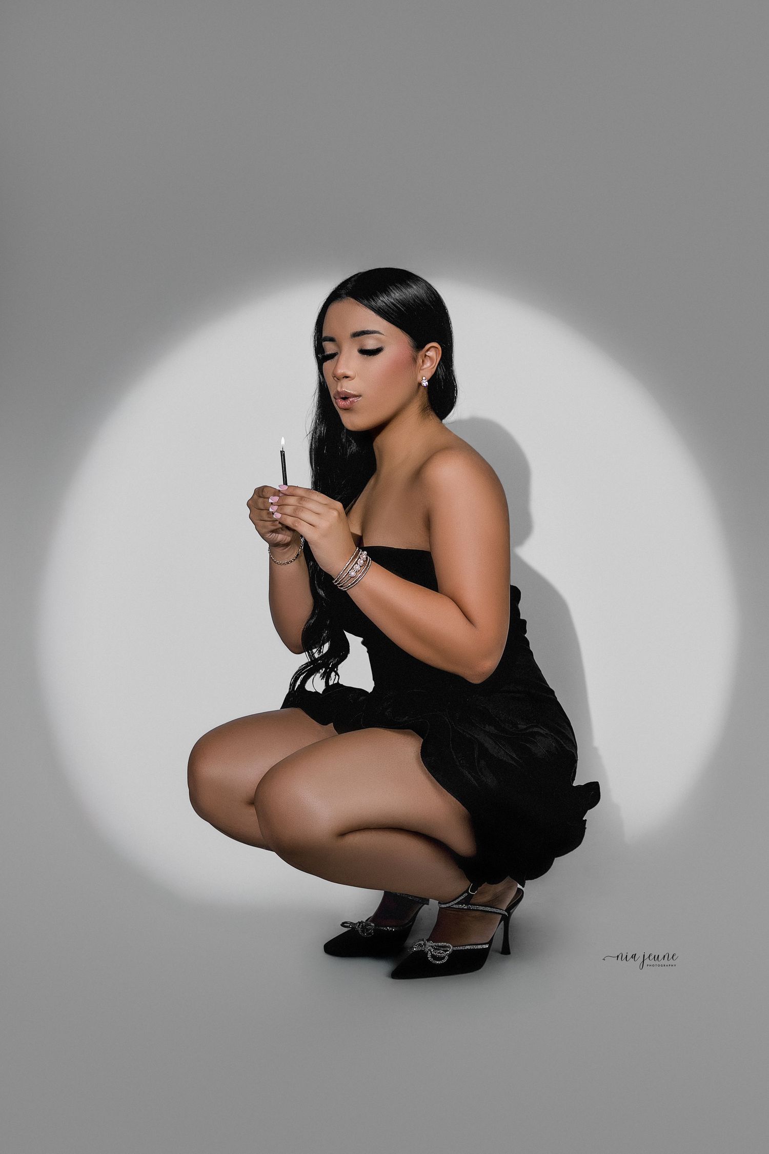 Artistic black and white photo series showing a woman in a black dress crouching in dramatic spotlight poses.