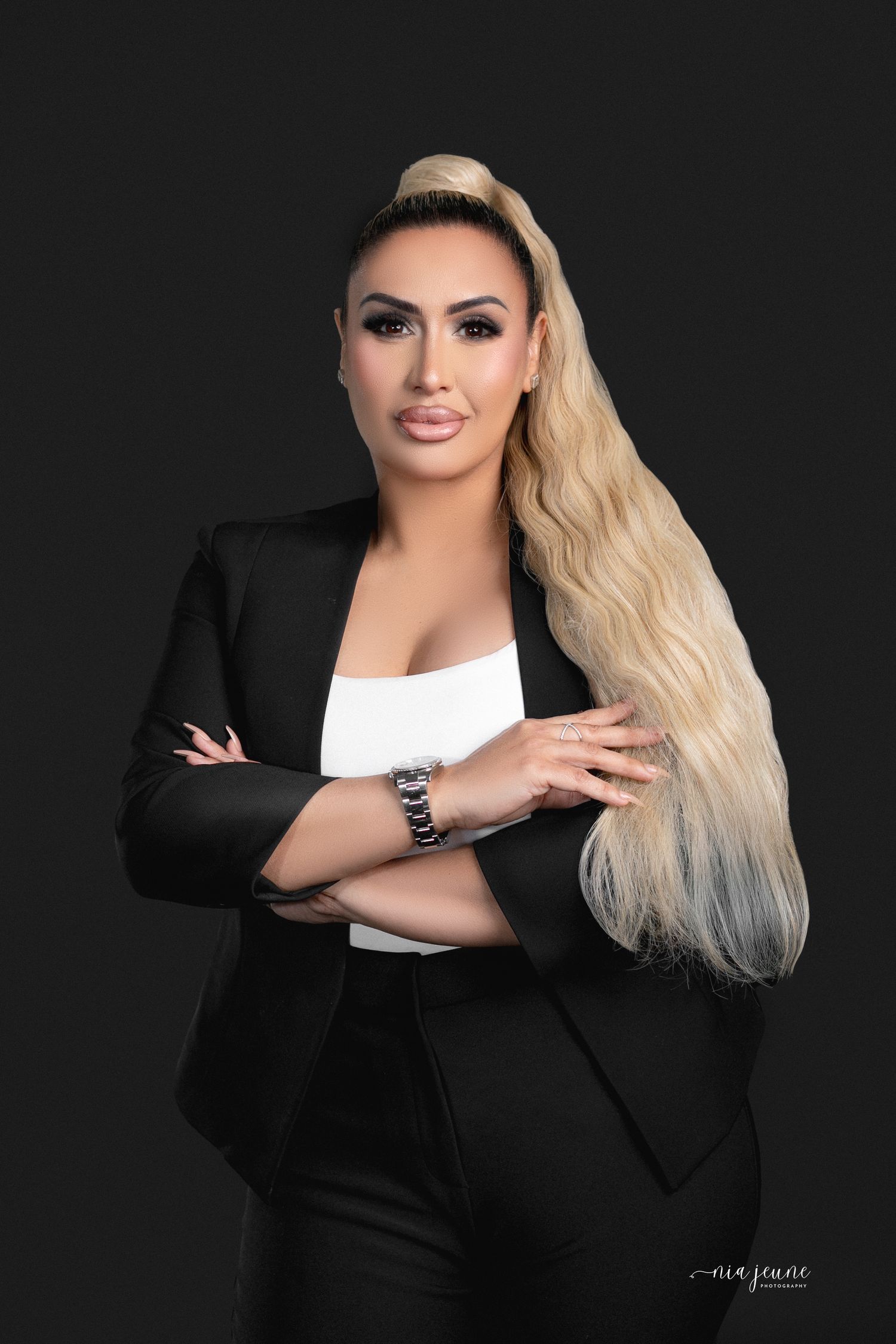 Professional portrait of a woman in business attire with long blonde hair against dark background.