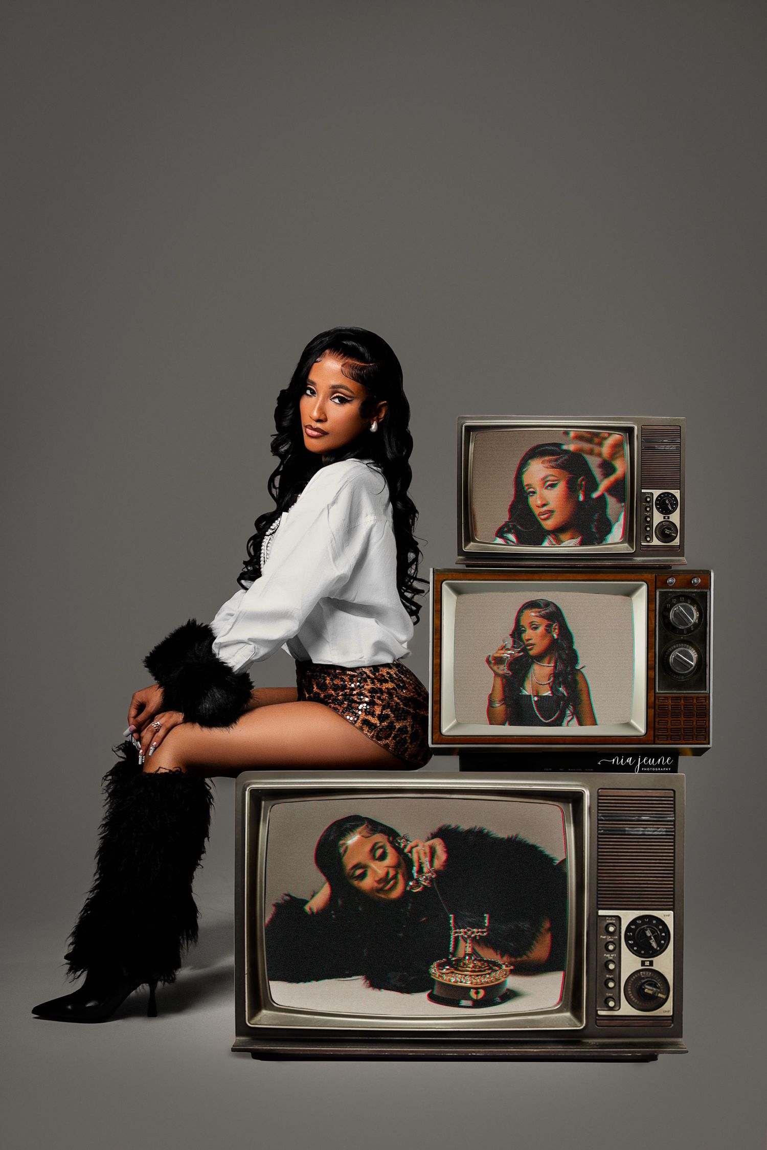 Fashion editorial scene with retro TV screens showing portraits and someone posed in leopard print shorts and white top.